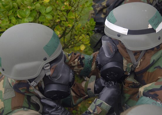 KUNSAN AIR BASE, Republic of Korea -- 8th Fighter Wing Airmen assist each other in donning  their gas mask here during exercise Beverly Midnight 10-03 Aug. 26. Using the buddy check system is helpful when in mission oriented protective posture to make sure all snaps on the chemical suit are fastened and the gas mask is on properly. (U.S. Air Force photo/Senior Airman Ciara Wymbs) 
