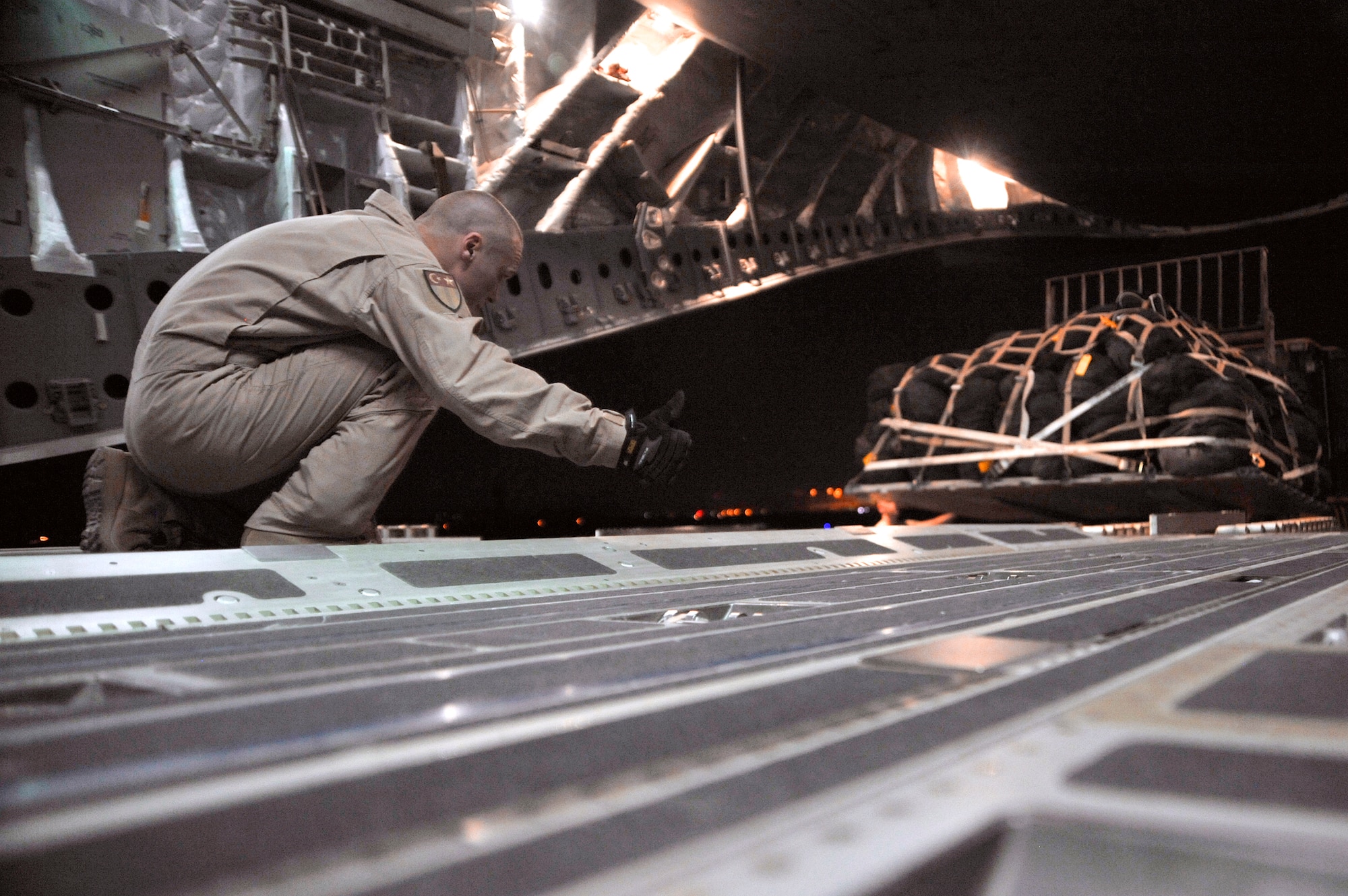 A C-17 Globemaster III loadmaster gives the thumbs up to 447th Expeditionary Logistics Readiness Squadron aerial porters while loading palletized baggage Aug. 6, 2010, at Sather Air Base, Iraq. (U.S. Air Force photo/Senior Airman Perry Aston)