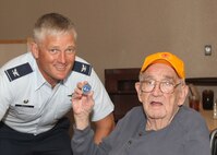 Dwight Gutzler shows off the commander's coin presented to him by Col. William H. Mott V, 37th Training Wing commander. (U.S. Air Force photo/Robbin Cresswell)