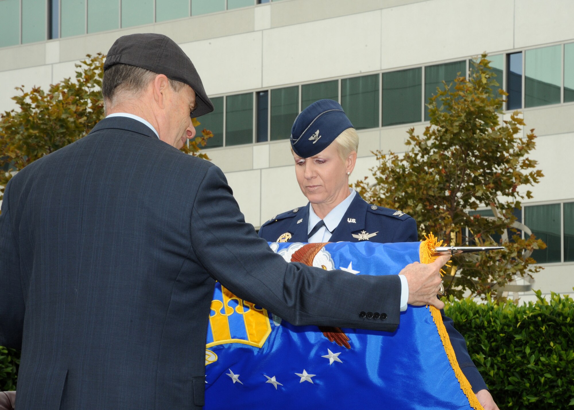 Colonel Anita Latin, 61st Air Base Wing commander, rolls up the ABW’s colors aided by Douglas Loverro, SMC executive director at a ceremony deactivating the wing, July 30. At the same ceremony, the 61st Air Base Group was reactivated under the command of Col. Frank Simcox.  (Photo by Lou Hernandez)