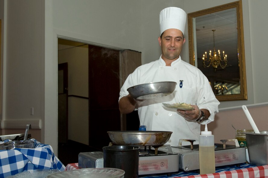 HANSCOM AIR FORCE BASE, Mass. – New chef, Mr. Reid Hannula, prepares to add ingredients at one of the chef action stations during the Taste of the Minuteman Club on Aug. 20. More than 50 people attended the special tasting in order to sample items from the club’s new catering menu. Those who signed up for catered services during the event received special discounts and door prizes were awarded for discounts on future events. (U.S. Air Force photo by Mark Herlihy)