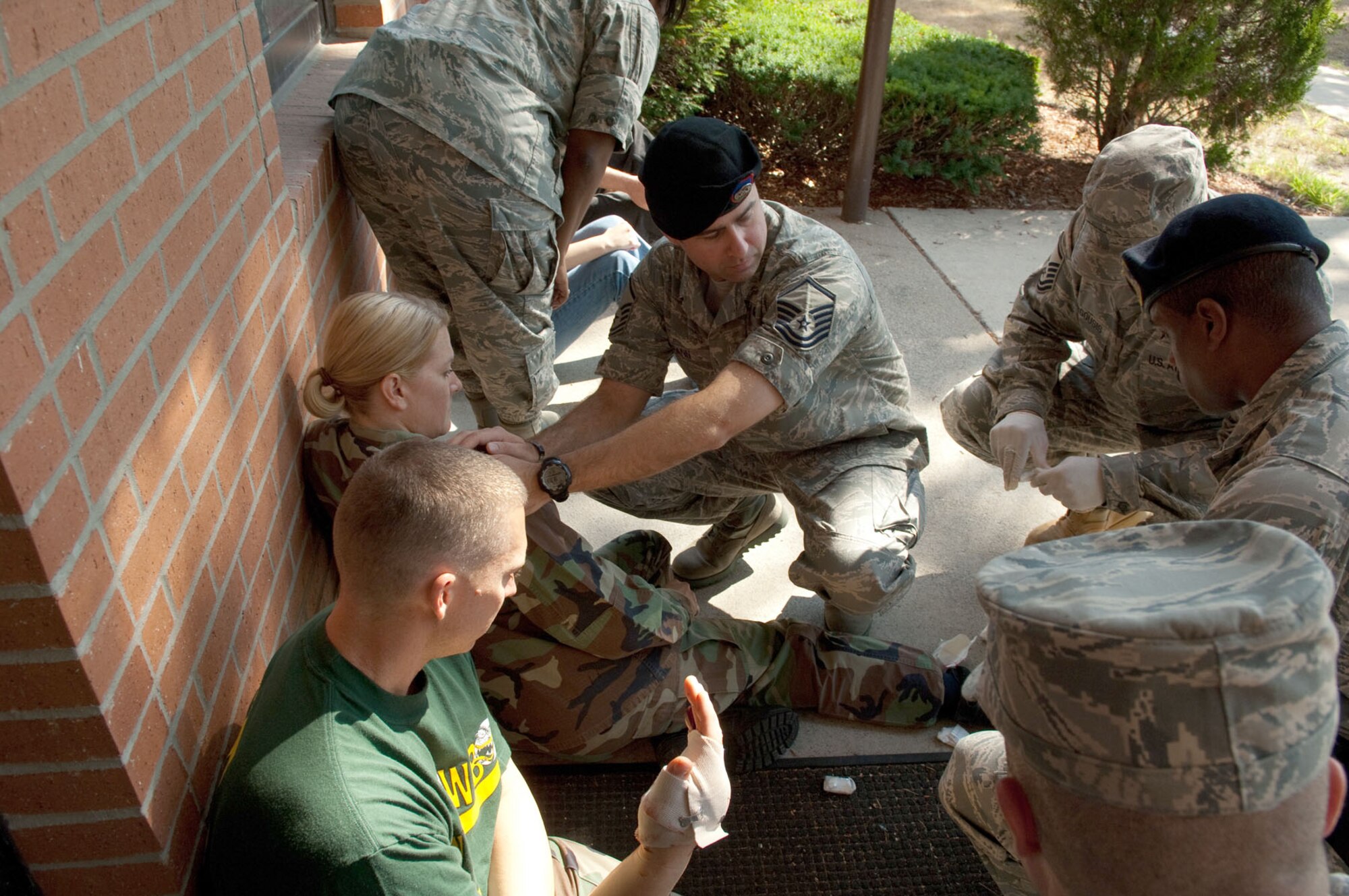 HANSCOM AIR FORCE BASE, Mass. – Master Sgt. Christopher Spann (middle) tends to the “wounded” during the base readiness exercise on Aug. 19. In the wake of the tragic shootings that took place recently in a workplace setting in Connecticut, as well as last November at Fort Hood, Texas, bases throughout the military are evaluating their own procedures and capabilities for handling an active shooter, should such an event take place on their doorstep. This exercise was part of a series of exercises to test the readiness of many of Hanscom’s emergency services. (U.S. Air Force photo by Rick Berry)