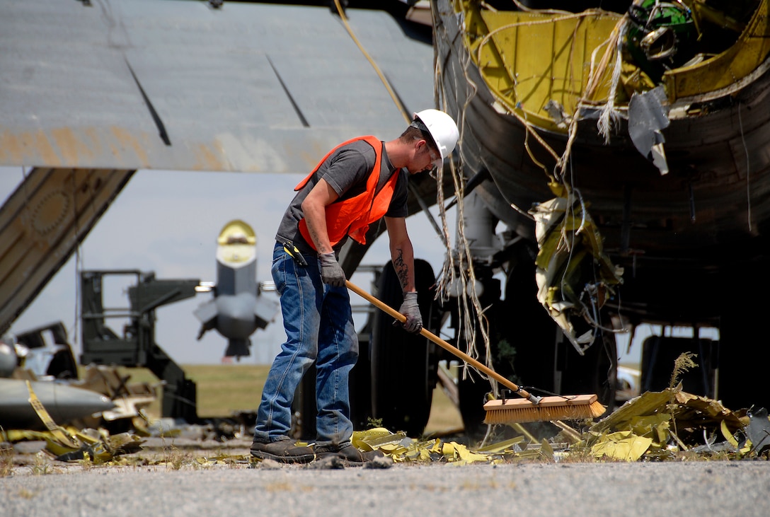 A contractor working with Navy Facilities Engineering Command, Engineering Center from Port Hueneme, Calif., sweeps up debris Aug. 24 during the demolition of a B-52G Stratofortress. The demolition is taking place on the old Strategic Air Command ramp north of the 80th Flying Training Wing. (U.S. Air Force photo/Mike Litteken