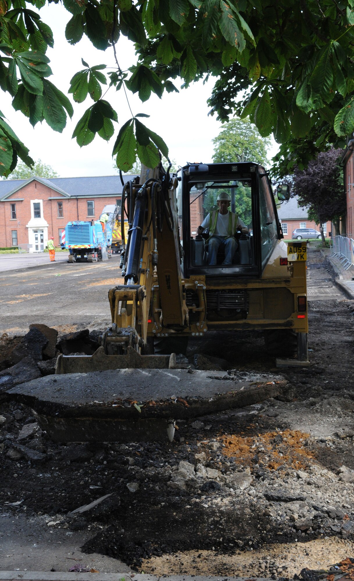 RAF MILDENHALL, England -- A contractor uses a backhoe to remove chunks of concrete that the road planer can't reach in Washington Square here. The square's transformation into a campus-like environment with sidewalks, lawns and trees allowed the 100th Civil Engineer Squadron to address sanitation and storm sewer repairs. (U.S. Air Force photo/Staff Sgt. Thomas Trower)
