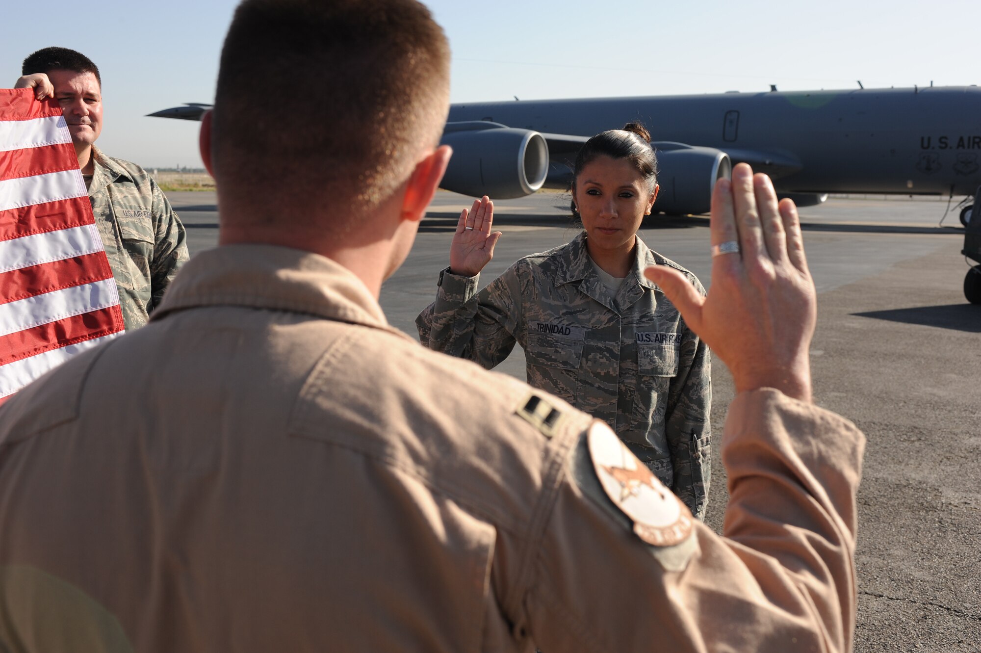 TRANSIT CENTER AT MANAS, Kyrgyzstan - Senior Airman Kathryn Trinidad reenlisted today for another four years in the Air Force with the help of Capt. Reed Goldberg. The flag, held by fellow members of the 376th Expeditionary Operations Group, was immediately folded and tucked into a KC-135 to immediately be flown over Afghanistan in support of Operation Enduring Freedom. Airman Trinidad is an intelligence analyst deployed from McConnell Air Force Base, Kan. (U.S. Air Force Photo/Tech. Sgt. Jennifer Buzanowski)