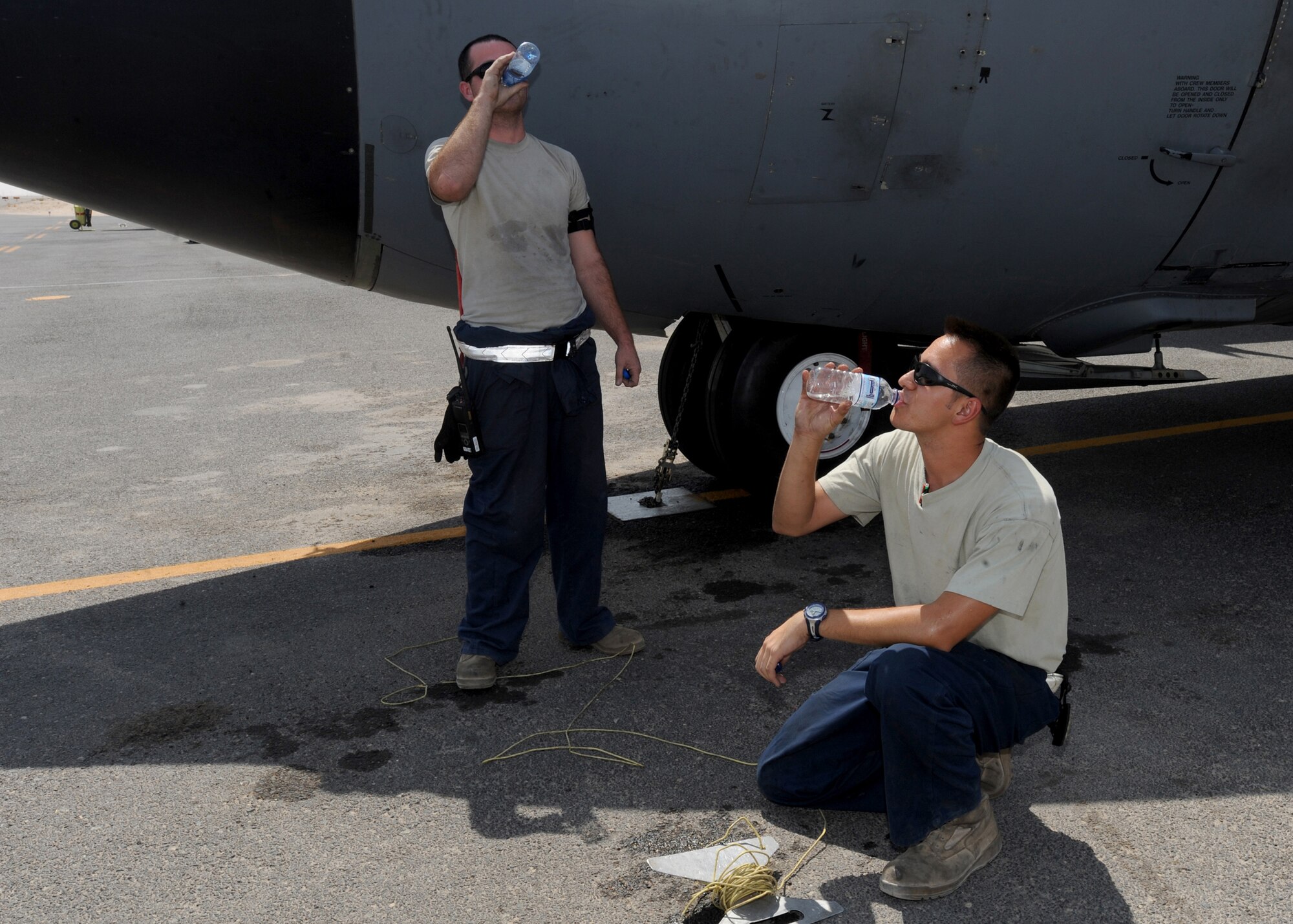 SOUTHWEST ASIA -- Airman 1st Class Neil Ortiz and Senior Airman Jonathon Wall, 386th Expeditionary Aircraft Maintenance Squadron crew chiefs, make sure to stay hydrated while working on the flightline here Aug. 21, 2010. Airmen who work outside for extended periods of time are considered to be at high risk for heat-stress illnesses. Commanders and base health officials are working to educate Airmen on how to stay healthy as they battle the elements. (U.S. Air Force photo by Senior Airman Laura Turner)