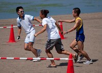 MISAWA AIR BASE, Japan -- Fusako Murphy and Maki Tashima, team "Super Murphy" swimmer and biker respectively, join hands with their third teammate, Hiromu Kubo, as he crosses the finish line at the base beach during Wild Weasel Triathlon 2010, Aug. 21. The trio won the team category, finishing with a time of 43 minutes, 47 seconds. (U.S. Air Force photo/Staff Sgt. Samuel Morse)