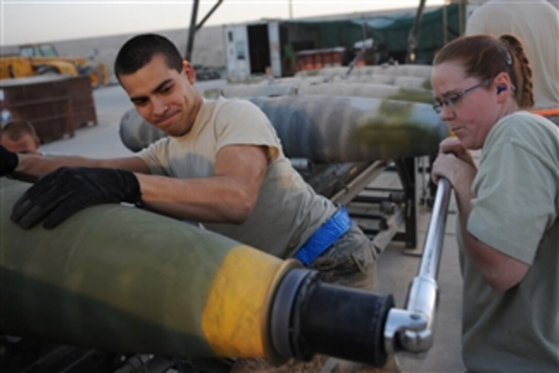 U.S. Air Force Airman 1st Class Anthony Anderson (left) holds a bomb in place as Staff Sgt. Misty Lowe tightens its super bolt at Kandahar Airfield, Afghanistan, on Aug. 23, 2010.  The airmen are munitions systems specialists with the 451st Expeditionary Maintenance Squadron Munitions Flight.  