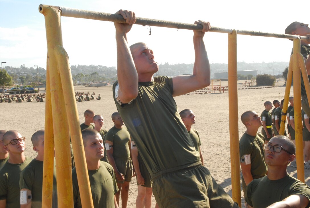 Recruit Jordan Butler, Platoon 1050, Company C. performs pull-ups during the first portion of his final PFT, 26 August.  For a pull-up to count the recruits must pull their chin clear over the bar and fully extend their arms on the way down.