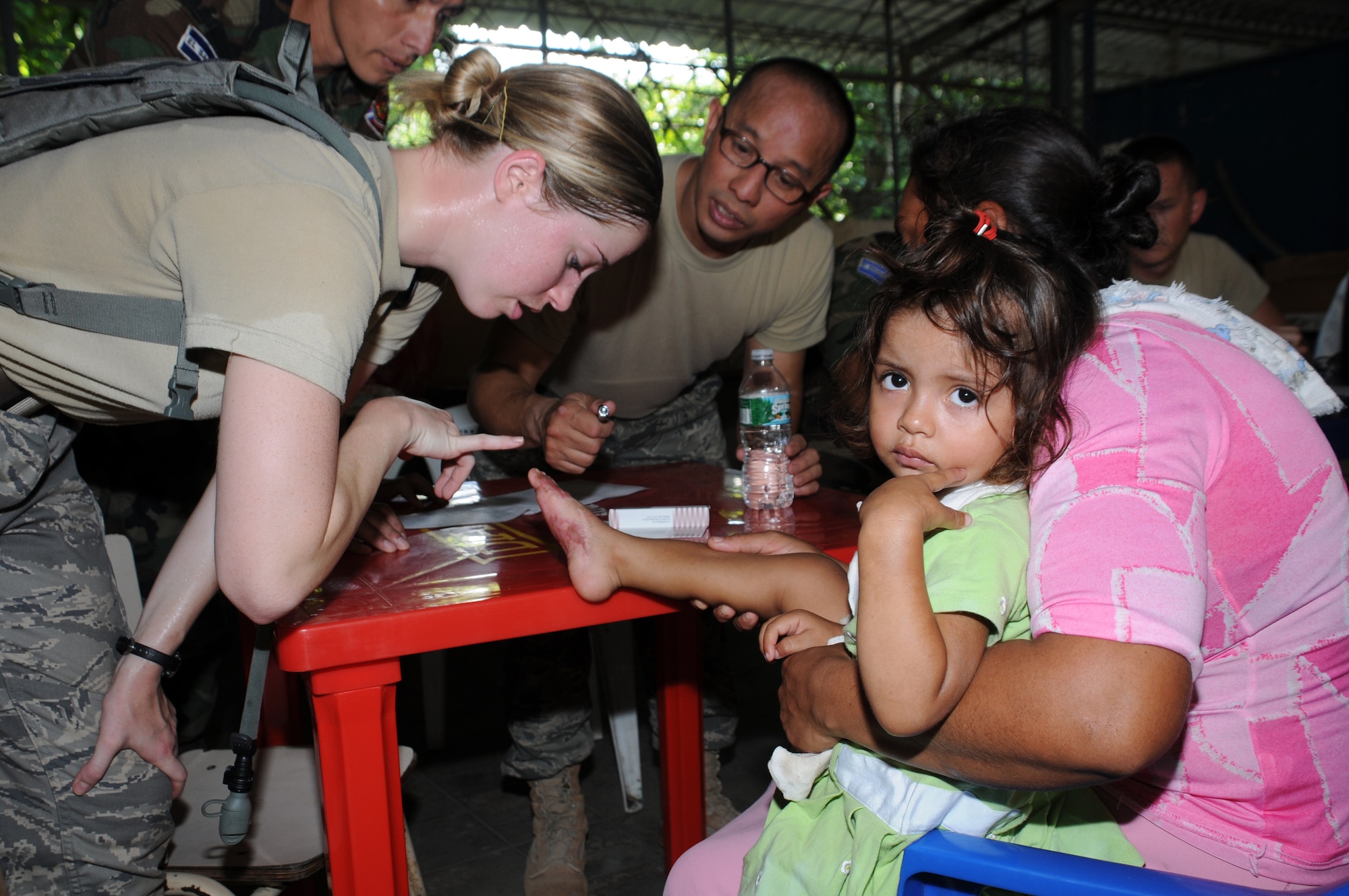 SAN CARLOS LEMPA, El Salvador --  In the screening room, 1st Lt. Nicole Musshorn, left, and Master Sgt. Wilson Gaspar, both with the Joint Task Force-Bravo Medical Element, examine a girls burned foot during the medical civic action program here Aug. 24. Team Bravo medical professinals assisted the El Salvador Ministry of Health and military in treating almost 800 patients here. (U.S. Air Force photo/Tech. Sgt. Benjamin Rojek)