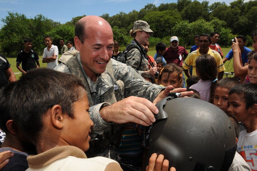 EL PICHICHE, El Salvador --  Dropping down the sunshade visor, Dr. (Col.) Michael Friedman, with the Joint Task Force-Bravo Medical Element, lets local children try on his helmet during the medical civic action program here Aug. 24. Team Bravo medical professionals assisted the El Salvador Ministry of Health and military in bringing medical care to more than 400 people in this remote village. (U.S. Air Force photo/Tech. Sgt. Benjamin Rojek)