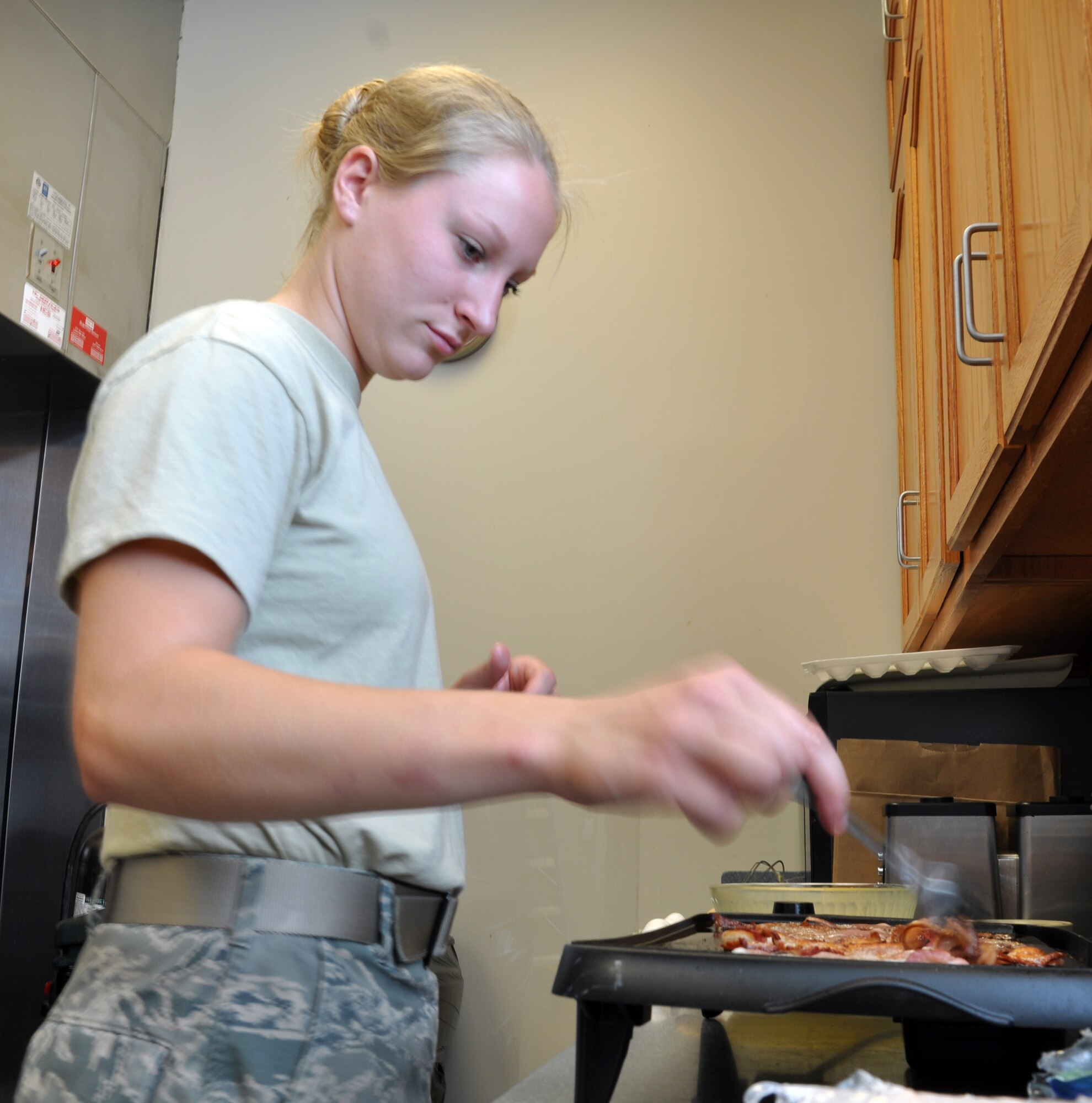 Airman 1st Class Brooke Rachocki, a public health technician with the 14th Medical Operations Squadron, cooks bacon for a chapel appreciation breakfast. Airmen from the enlisted dorms cooked breakfast to thank the chapel for their support. (U.S. Air Force photo/Airman 1st Class Hedrick)