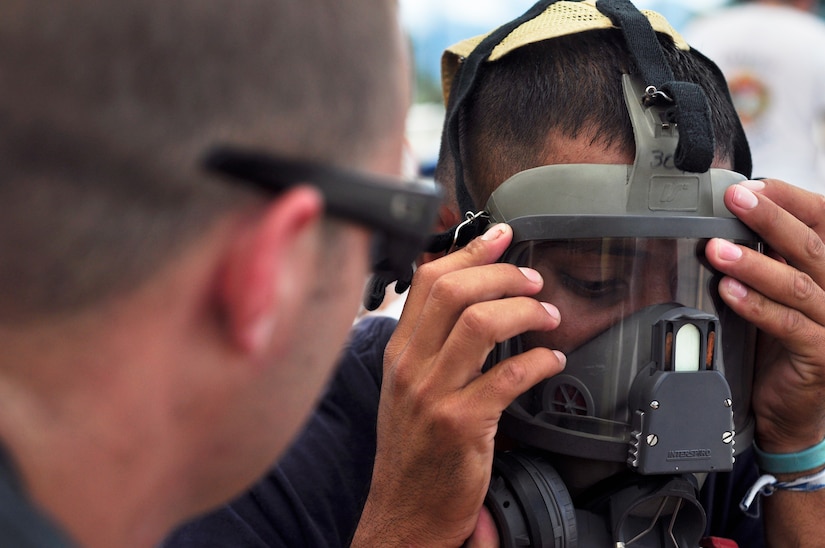 SOTO CANO AIR BASE, Honduras --  Making sure his mask is properly sealed, Denis Ponce, a Honduran firefighter, gets geared up for a training scenario as Senior Airman Andrew Fruehan, a 612th Air Base Squadron firefighter, assists him during the Central America Sharing Mutual Operational Knowledge and Experiences exericse here Aug. 24. This year's firefighter training exercise included firefighters from Honduras, the 612th Air Base Squadron and, for the first time, Guatemala. (U.S. Air Force photo/Martin Chahin)