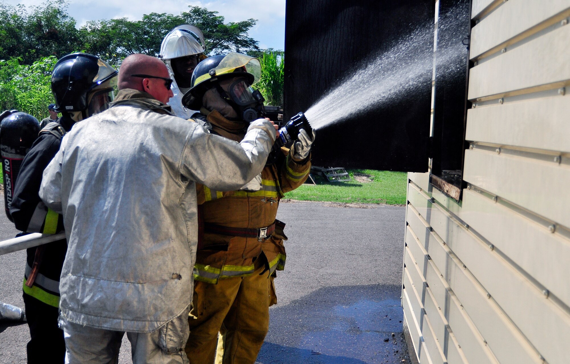 SOTO CANO AIR BASE, Honduras --  Spraying water through an open window, firefighters from the 612th Air Base Squadron train and train with Honduran and Guatemalan firefighters during the Central America Sharing Mutual Operational Knowledge and Experiences exericse here Aug. 26. This was the first time Guatemala participated in the annual exercise. (U.S. Air Force photo/Martin Chahin)