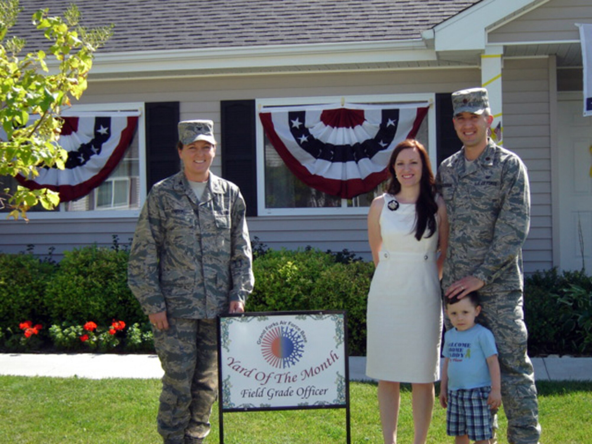 Col. Tammy Knierim, 319th Mission Support Group commander, presents Maj. Ernest Calderon, 319th Air Refueling Wing Judge Advocate, and his family with the July 2010 Yard of the Month, Field Grade Officer Category. The yard of the month program recognizes the hard work and effort of base residents that exceed the yard maintenance standards. (Courtesy photo)