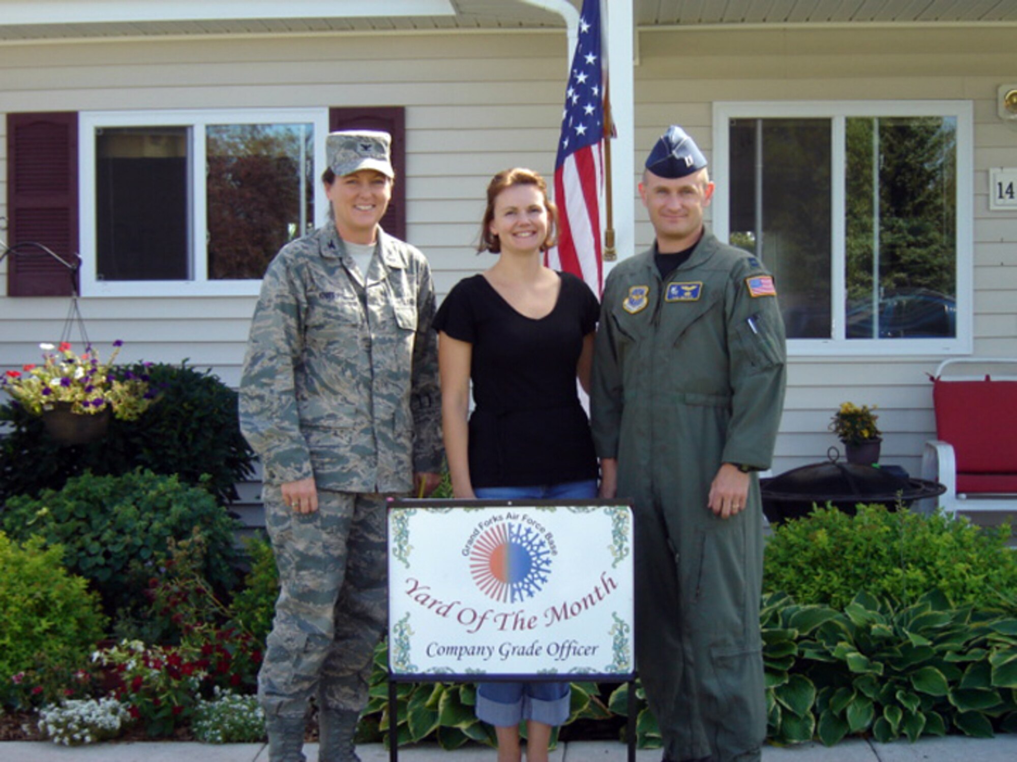 Col. Tammy Knierim, 319th Mission Support Group commander, presents Capt. Johnathan Walker, 905th Air Refueling Squadron, and his wife with the July 2010 Yard of the Month, Company Grade Officer Category. The yard of the month program recognizes the hard work and effort of base residents that exceed the yard maintenance standards. (Courtesy photo)