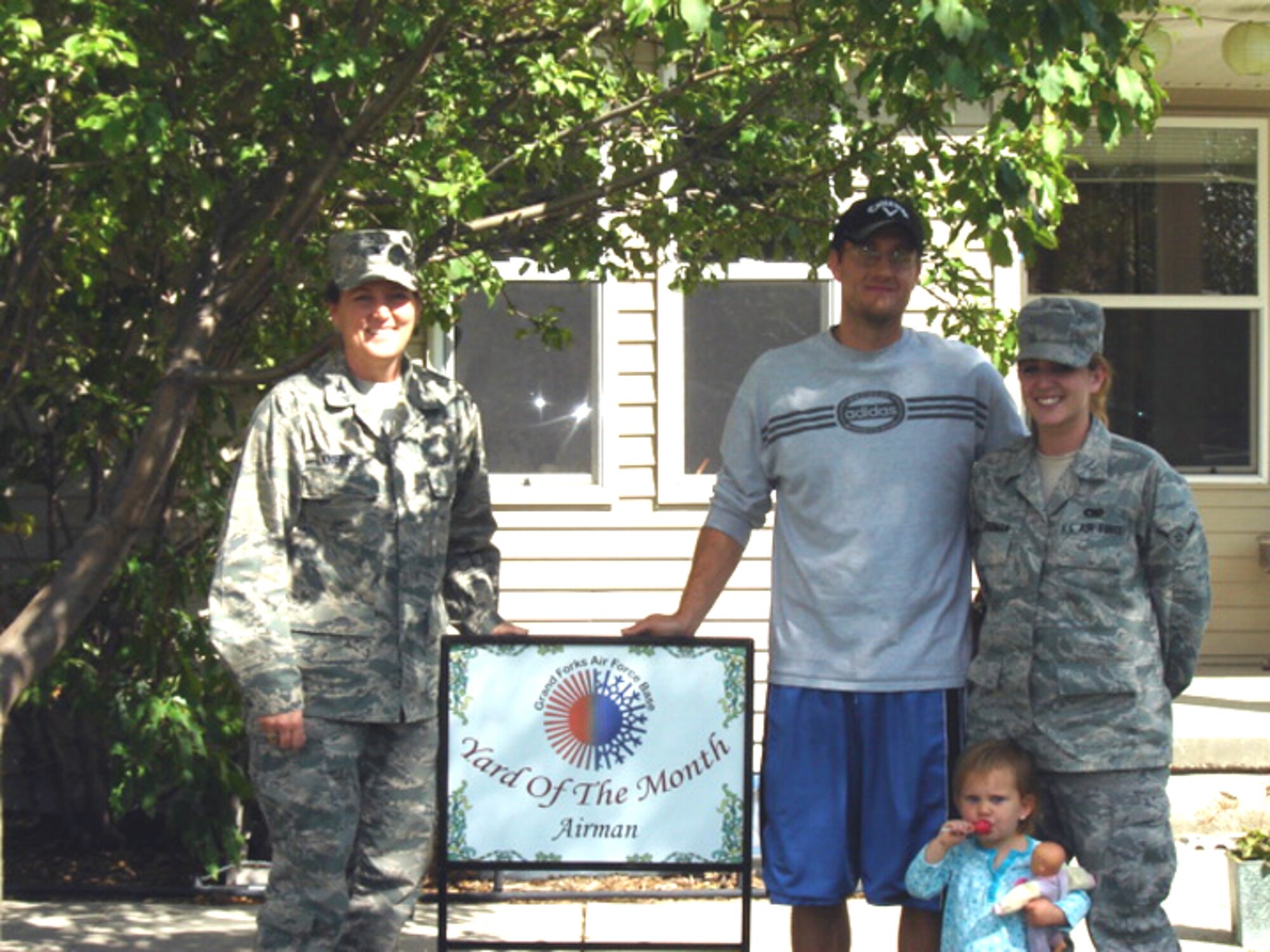Col. Tammy Knierim, 319th Mission Support Group commander, presents Airman Keilynn Watermen, 319th Logistics Readiness Squadron, and her family with the July 2010 Yard of the Month, Airman Category. The yard of the month program recognizes the hard work and effort of base residents that exceed the yard maintenance standards. (Courtesy photo)