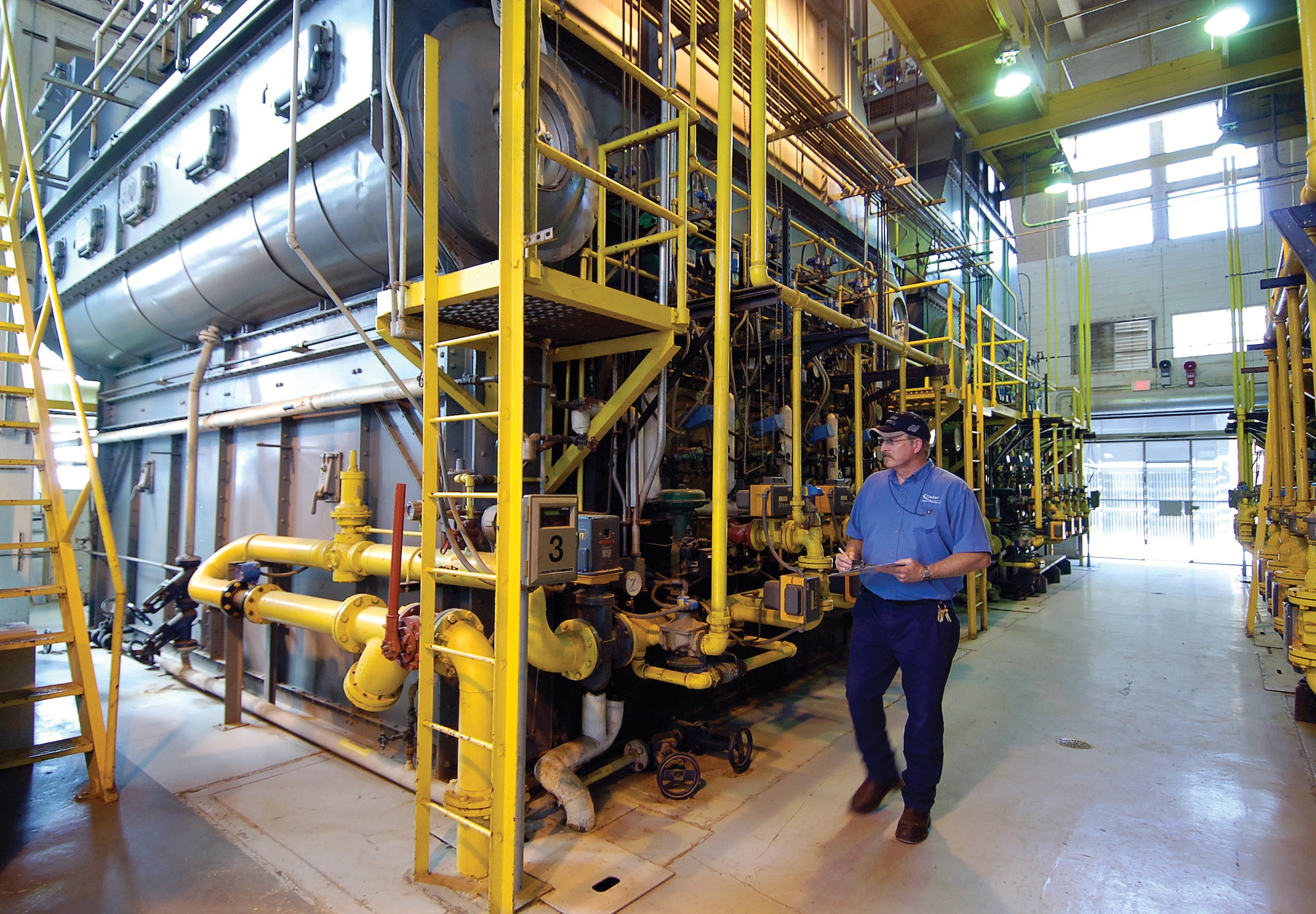 In Bldg. 208, boilers loom high over plant supervisor Ko’be Galloway. Before microwave ovens or credit cards were created, a boiler in Bldg. 208 was built that still produces steam for Tinker’s industrial processes and provides personal heat for workers during winter. (Air Force photo by Margo Wright)