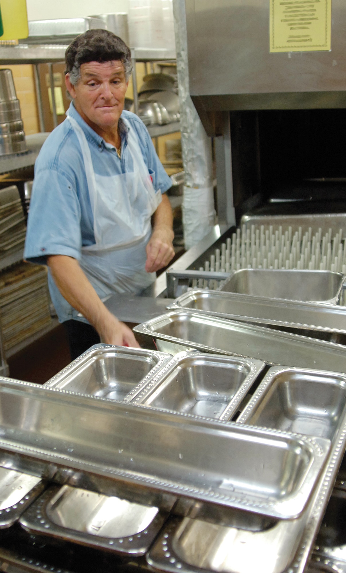 Café 3001 dishwasher Kinnie Hyden removes clean serving pans from an automated dishwasher. The steaming hot water that cleans the pans and travels to buildings across base comes from equipment that has been on base for decades. (Air Force photo by Margo Wright)