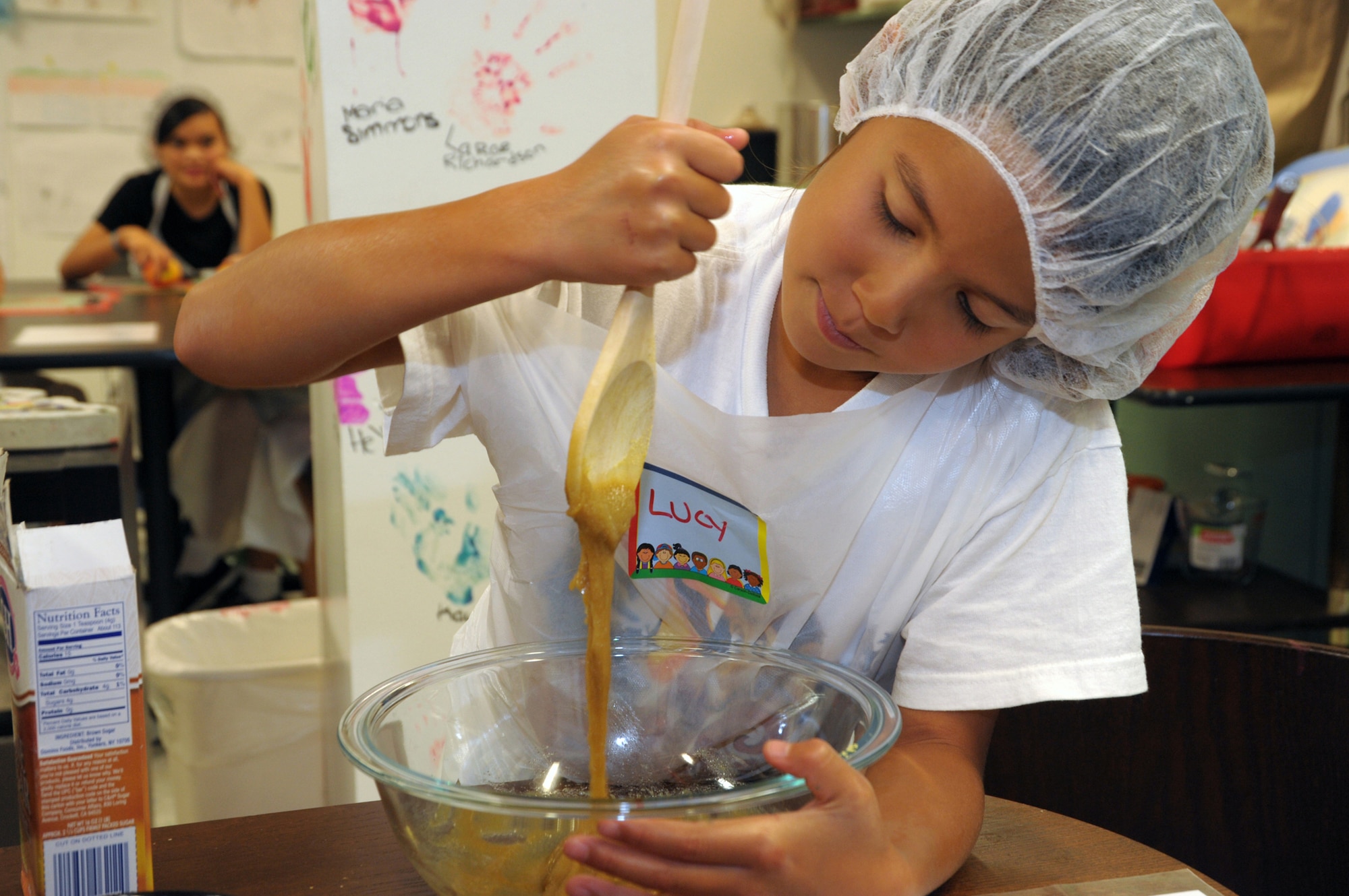 A camper mixes together the ingredients for a ham glaze. The kids blanched peaches and apricots, cooked a glazed ham, steamed snap peas and baked sweet potatoes while learning about good nutrition and food safety.  (Photo by Joe Juarez)