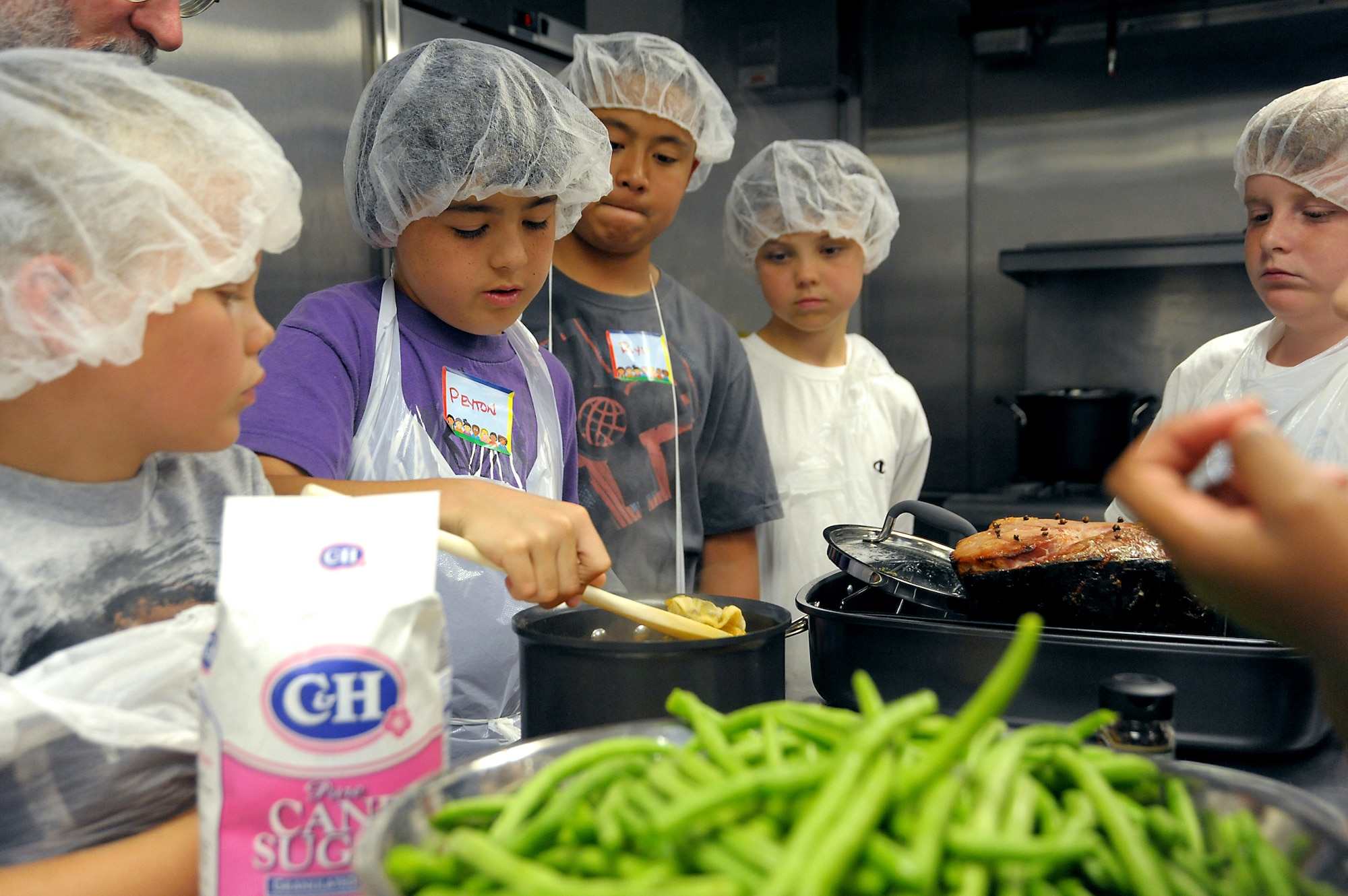 4-H culinary campers work together to prepare a meal as part of the recent camp taught by Aaron Reaven from “Chef-K.”  (Photo by Joe Juarez)