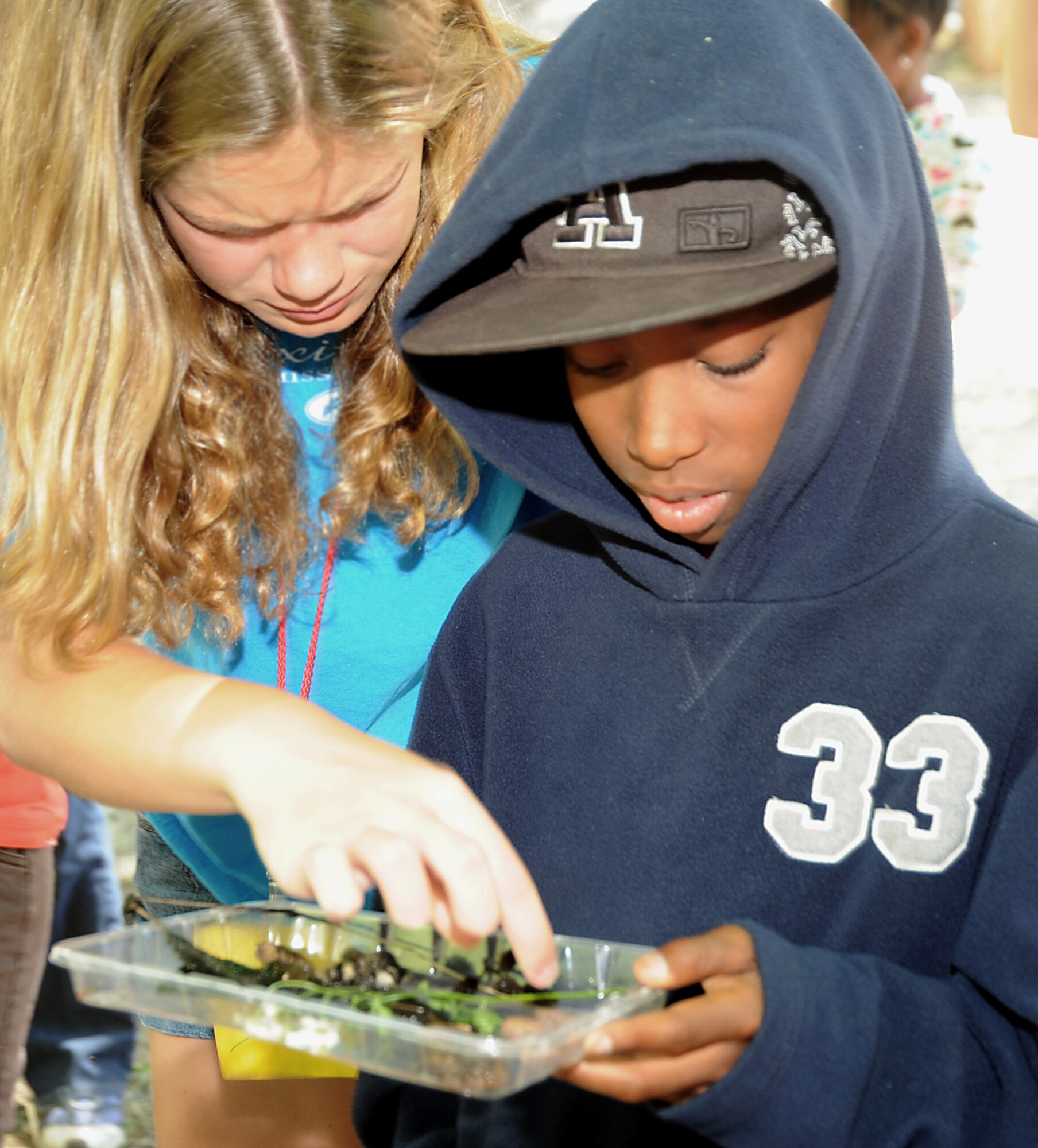 Family members Brianna Osborne (left) and Chance Coley study a water sample taken from a nearby creek, as part of an environmental lesson at Camp Seeley, June 30.  (Photo by Joe Juarez)