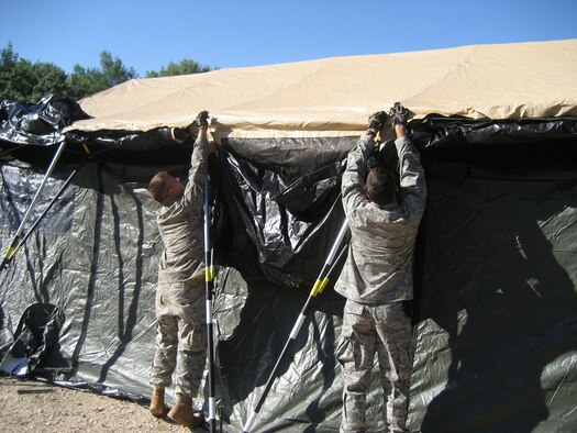 1st Lt. Jeffrey Buchholtz, right, and Senior Airman Ben Rasine, left, both 1st Special Operations Civil Engineer Squadron J-Team, secure a tent door during Operation Jackal Stone in Croatia, September 2009. The J-Team is comprised of engineering specialists who enable special operations forces by providing resources to sustain their presence for weeks wherever they are required. (Courtesy photo from U.S. Air Force Master Sgt. James Jarvis)