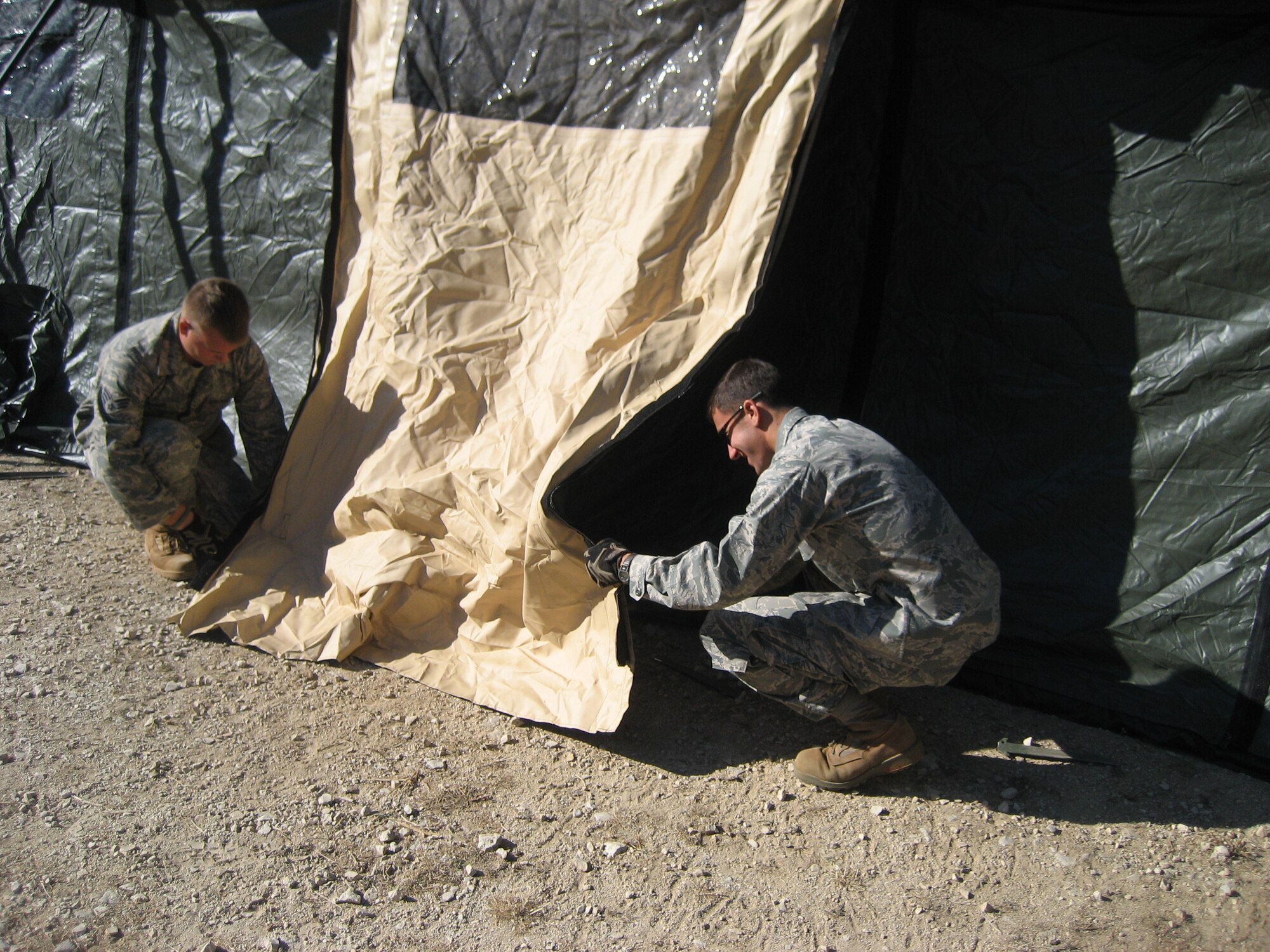 1st Lt. Jeffrey Buchholtz, right, and Senior Airman Ben Rasine, left, both 1st Special Operations Civil Engineer Squadron J-Team, secure a tent door during Operation Jackal Stone in Croatia, September 2009. The J-Team is comprised of engineering specialists who enable special operations forces by providing resources to sustain their presence for weeks wherever they are required. (Courtesy photo from U.S. Air Force Master Sgt. James Jarvis)