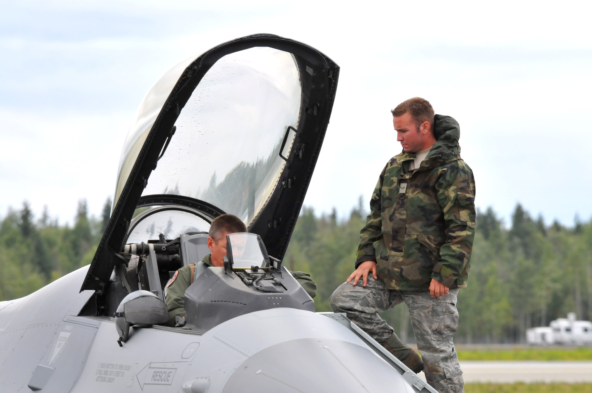 Airman 1st Class Jake Rasmussen, crew chief for the 115th Aircraft Maintenance Squadron, assists a pilot into the cockpit of the F-16 Fighting Falcon, during a Red Flag exercise, Eielson AFB, Alaska Aug. 18. Rasmussen deployed to Eielson in support of the 115th Fighter Wing out of Madison, Wis. (Wisconsin Air National Guard photo by Tech Sgt. Ashley Bell)