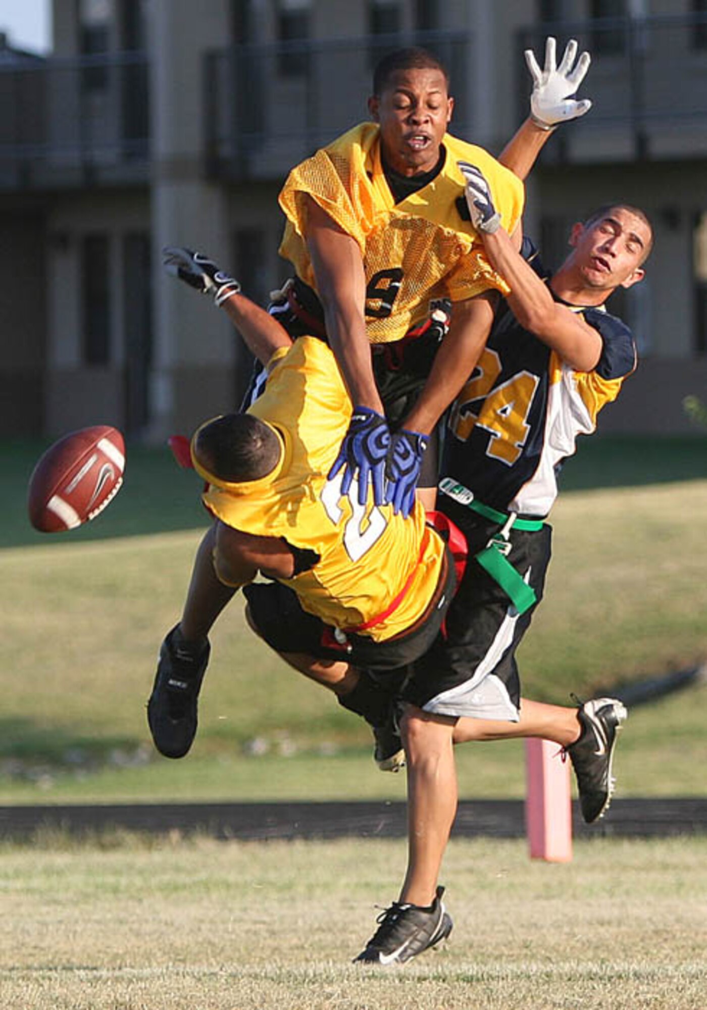 Tinker Reserve flag football defensive back Mario Cruz (bottom) collides with fellow teammate Eric Wooten (top) and Navy receiver Jorge Esparza during a game held on Tinker AFB, Oklahoma on Aug. 12.  Navy won the game 12-0.  