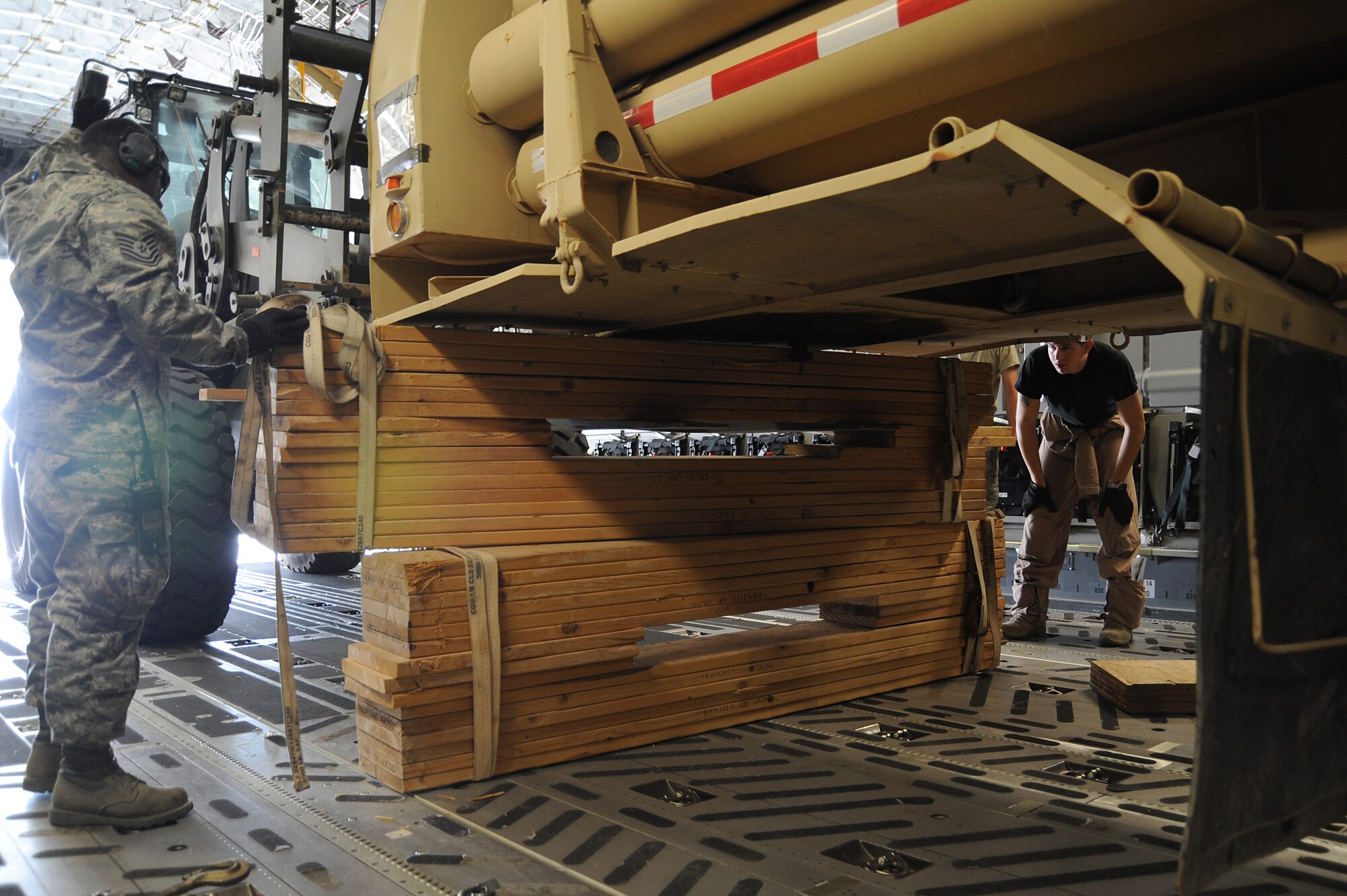 Tech. Sgt. Joseph Munn, 380th Expeditionary Logistics Readiness Squadron non-commissioned officer in charge Air Terminal Operations Center, directs the placement of wooden beams to secure a 25 foot bulk helium trailer as part of a helium loading mission Aug 24 at a non-disclosed base in Southwest Asia. The 380th ELRS delivers approximately 90,000 pounds of helium per week to the Area of Responsibility.  (U.S. Air Force Photo/Tech. Sgt. April Wickes) 