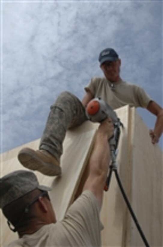 U.S. Air Force Tech. Sgt. Douglas McMullin and Staff Sgt. Zachery Jones, both with the 777th Expeditionary Prime Base Engineer Emergency Force Squadron, use a pneumatic nail gun to secure a wall of a medical aid station at Access Control Station 2, Kandahar City, Afghanistan, on Aug. 2, 2010.  