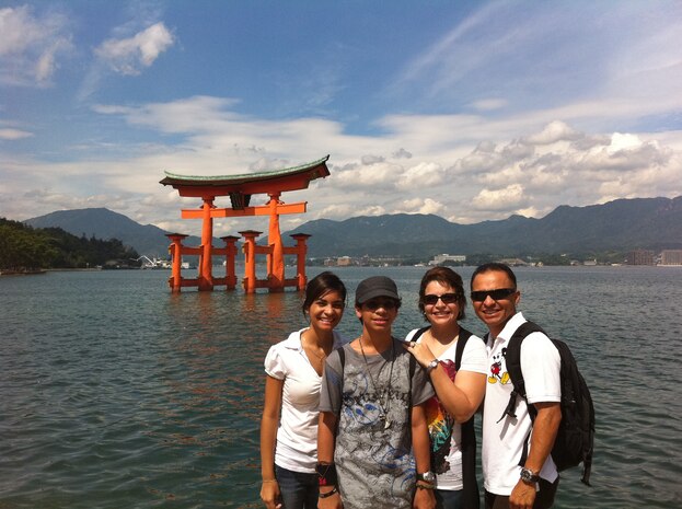 (From right) Staff Sgt. Jay M. Santiago, Headquarters and Headquarters Squadron staff-noncommissioned officer in charge, poses with his family, Madelyn Santiago, Joshten::r::::n::Santiago and Destynee Santiago in front of the Miyajima Torii, the floating gate Itskushima shrine in Miyajma, Japan, last year. Santiago survived the terrorist attacks September::r::::n::11, 2011. When the South tower collapsed Santiago was trapped under a trailer with five other people for hours before being rescued by firemen.