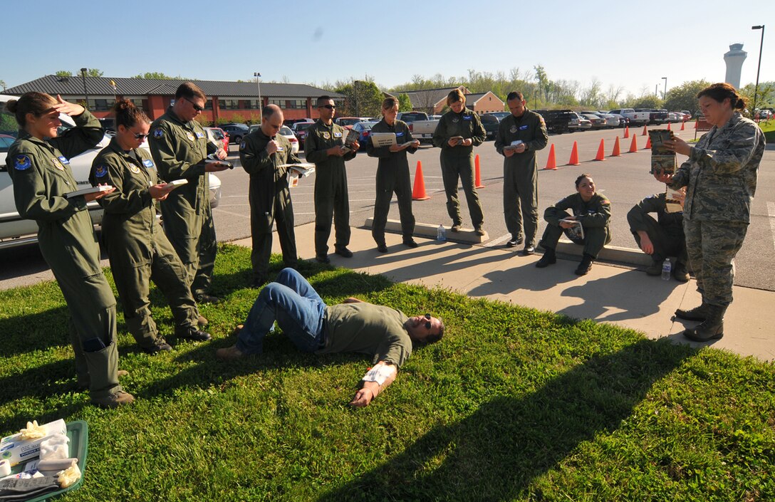 932nd Airlift Wing members read over self aid and buddy care reminders in their Airman's Manual during a training weekend near Belleville, Ill. A "patient" was on hand for realism.  They were participating in a special Ability to Survive and Operate course at the Air Force Reserve Command wing. (U.S. Air Force photo/Maj. Stan Paregien)