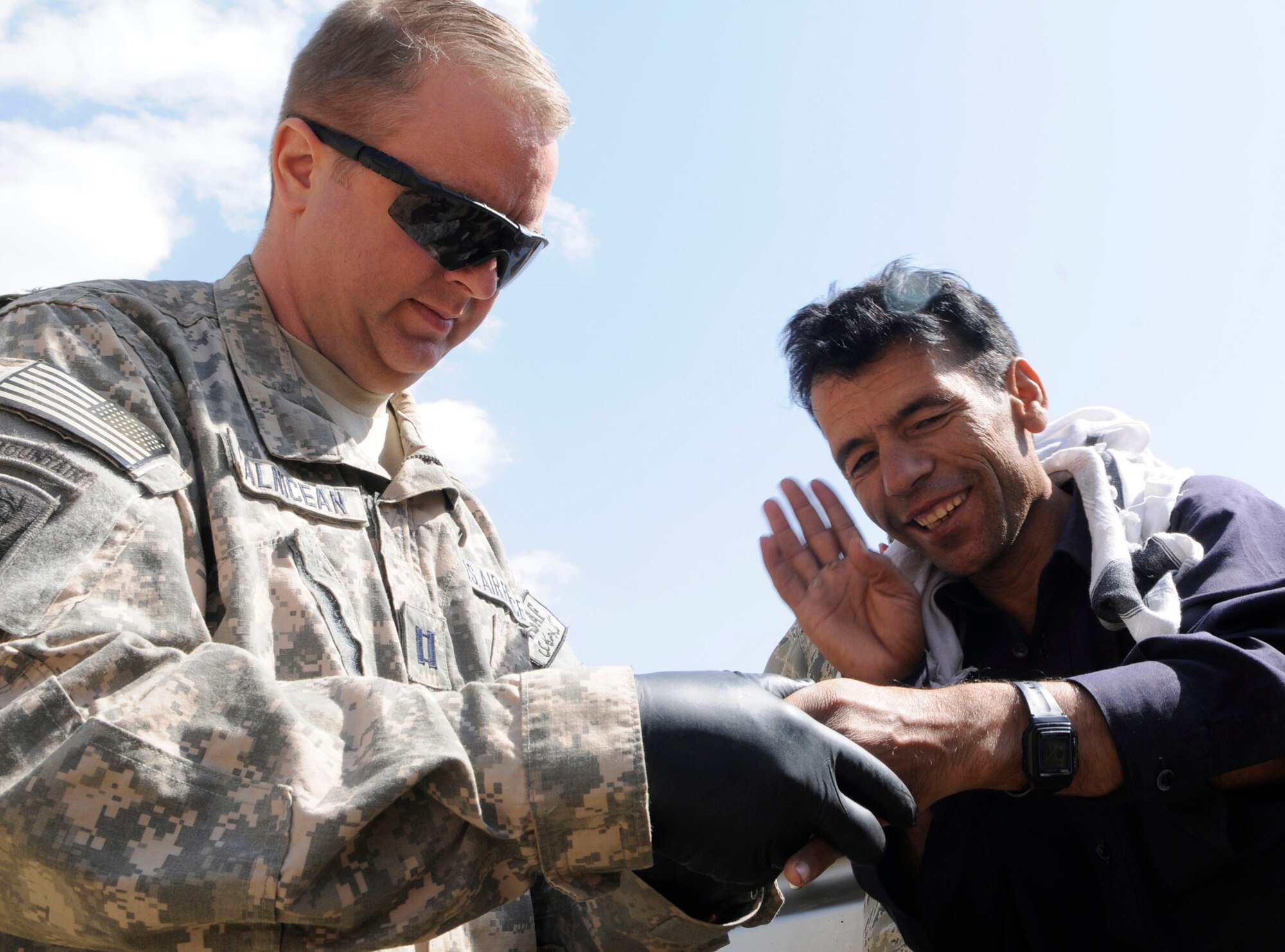 During a stop at the Khenj Afghan National Police station a local man approached member of Provincial Reconstruction Team Panjshir for medical assistance.  U.S. Air Force Captain Michael Calnicean, Forward Operating Base Lion chief medical officer from Detroit Mi., examined the gentleman and identified several infected cuts caused by a skin infection of his left hand.  After cleaning the infected area Capt Calnicean applied a clean dressing and provided the patient with several clean dressing along with instructions on how to change the dressing and to keep the infected area clean.  (U.S. Air Force photo by: Tech. Sgt. Sean Mateo White, PRT Panjshir photographer)