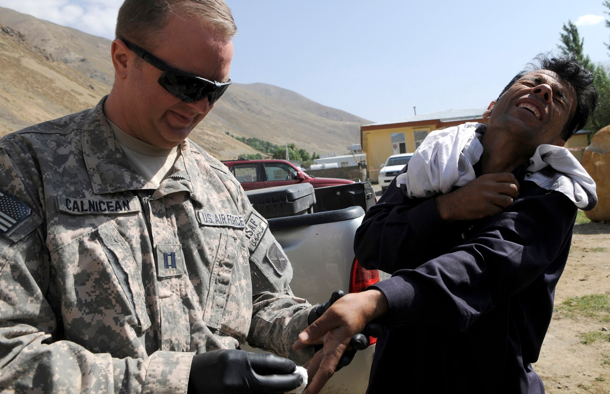 During a stop at the Khenj Afghan National Police station a local man approached member of Provincial Reconstruction Team Panjshir for medical assistance.  U.S. Air Force Captain Michael Calnicean, Forward Operating Base Lion chief medical officer from Detroit Mi., examined the gentleman and identified several infected cuts caused by a skin infection of his left hand.  Capt Calnicean flushed the infected areas with saline and applied a clean dressing over the infected areas. (U.S. Air Force photo by: Tech. Sgt. Sean Mateo White, PRT Panjshir photographer)