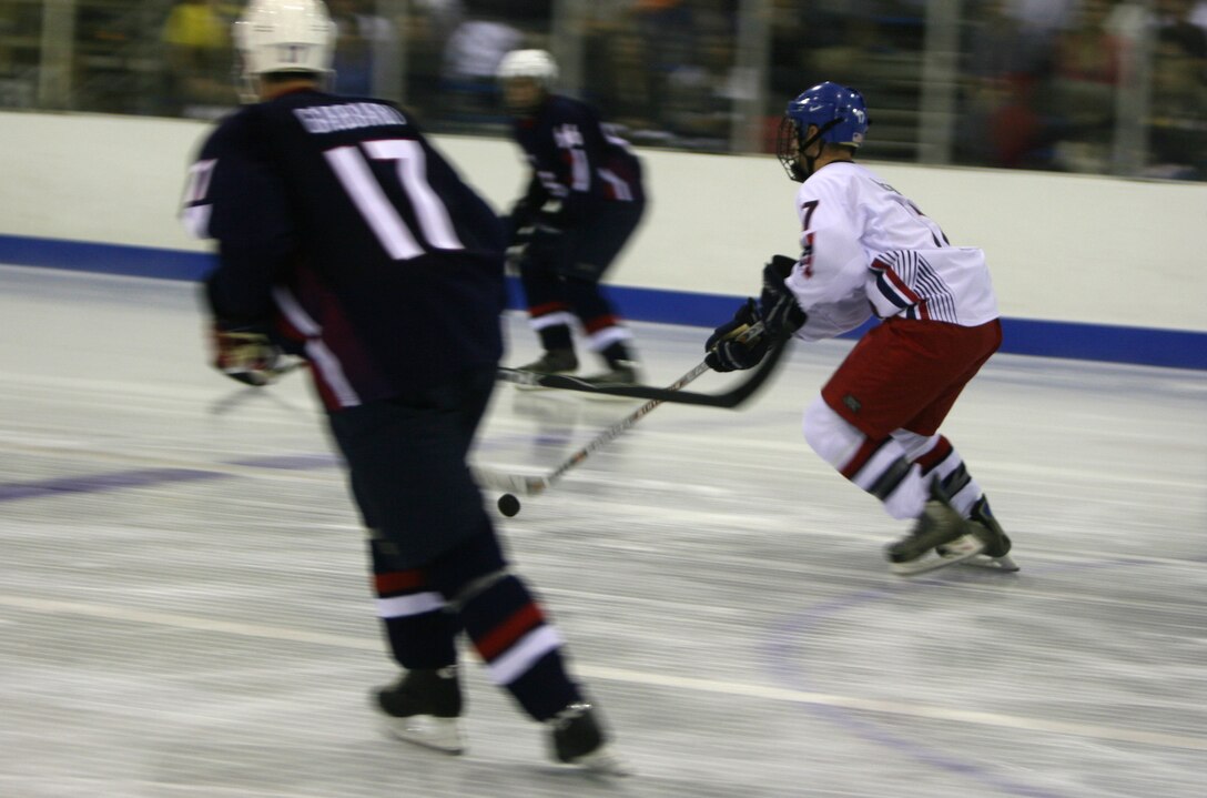 Anthony Klem, forward for the Army, Air Force team, races down the ice as members of the Navy, Marine, Coast Guard team look to defend during the first-ever Wounded Warriors Charity Hockey Game Aug. 29 at the Ice Palace, Aiea, Hawaii. The Army, Air Force team took the win 5-3.