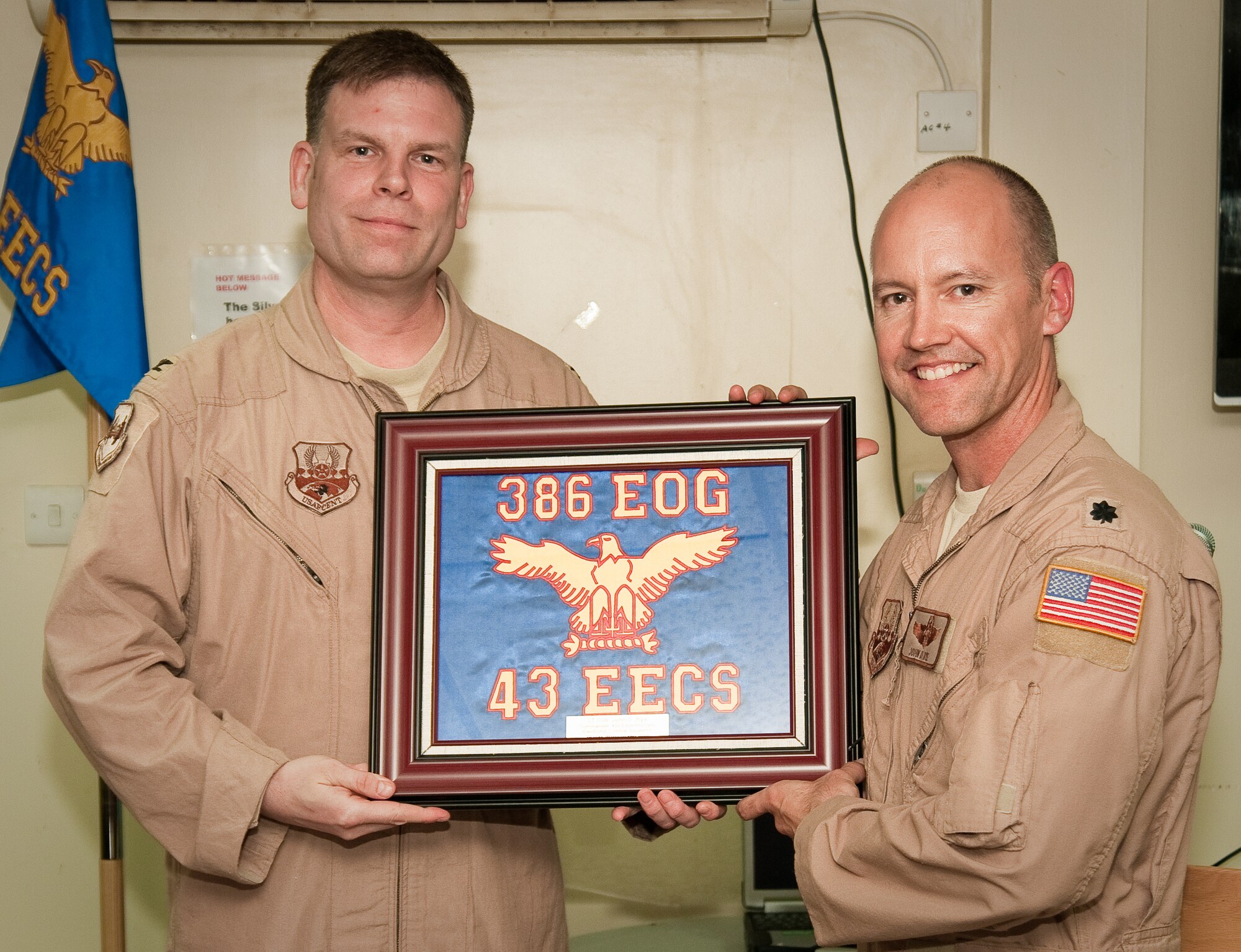 SOUTHWEST ASIA - Col. Scott Brewer (left), commander of the 386th Expeditionary Operations Group, presents a framed 43rd Expeditionary Electronic Combat Squadron flag to the 43rd's commander, Lt. Col. J.D. Rye, during a farewell dinner here Aug. 27, 2010. The 43rd EECS has been part of the 386th Air Expeditionary Wing here for 6 1/2 years but is moving to another base in the U.S. Central Command area of responsibility becuase of the responsible drawdown of forces in Iraq. (U.S. Air Force photo by Maj. Dale Greer/Released)
