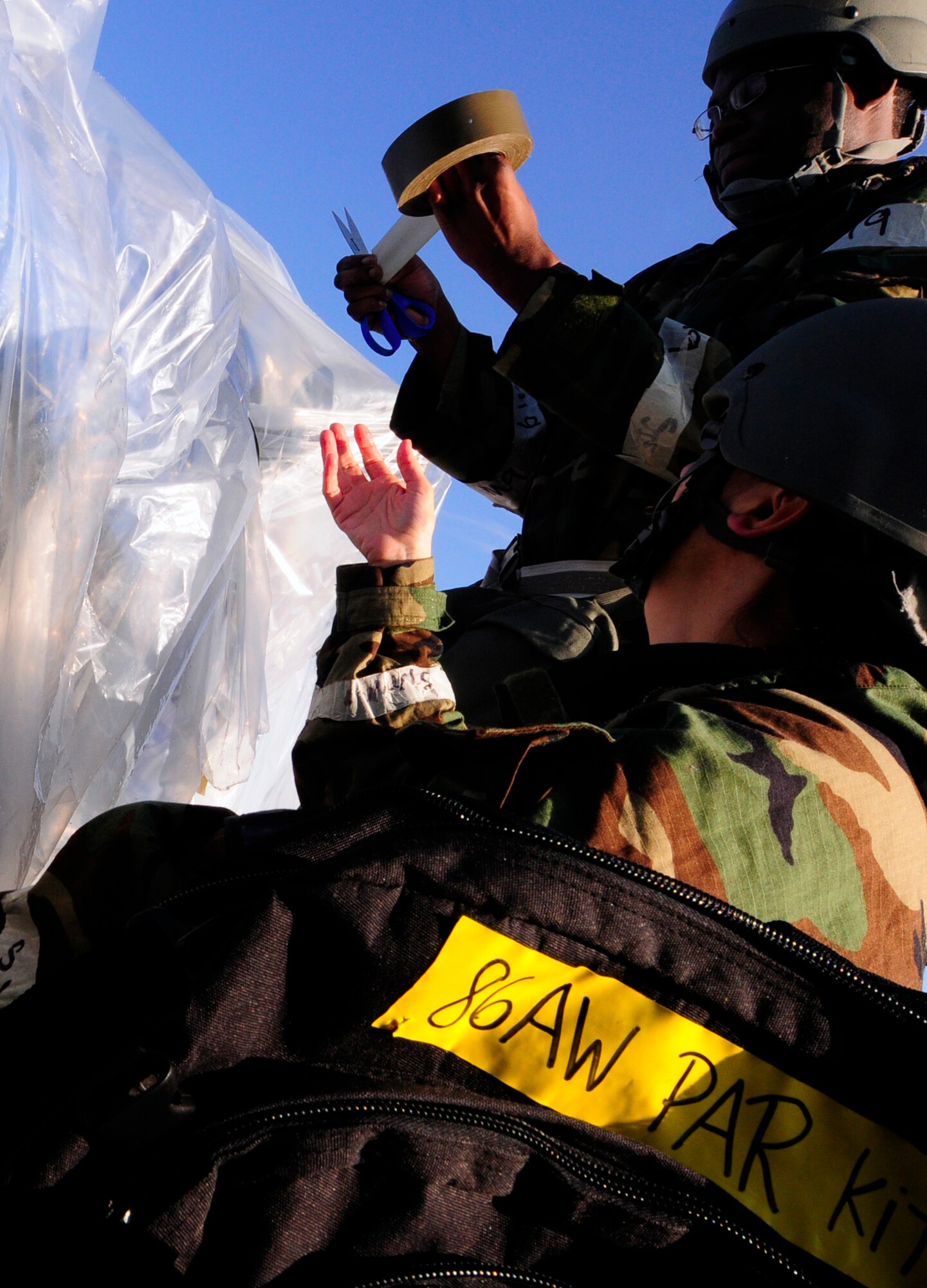 U.S. Air Force Tech. Sgt. Maria Franz and Senior Airman Bruce Porter, 86th Airlift Wing Judge Advocate's office paralegals, secure a vehicle with plastic covering to protect it from chemical contamination during an operational readiness exercise (ORE), Ramstein Air Base, Germany, Aug. 28, 2010. An ORE incorporates a series of scenarios to evaluate a base's ability to execute operational duties under simulated wartime conditions. (U.S. Air Force photo by Airman 1st Class Brea Miller)