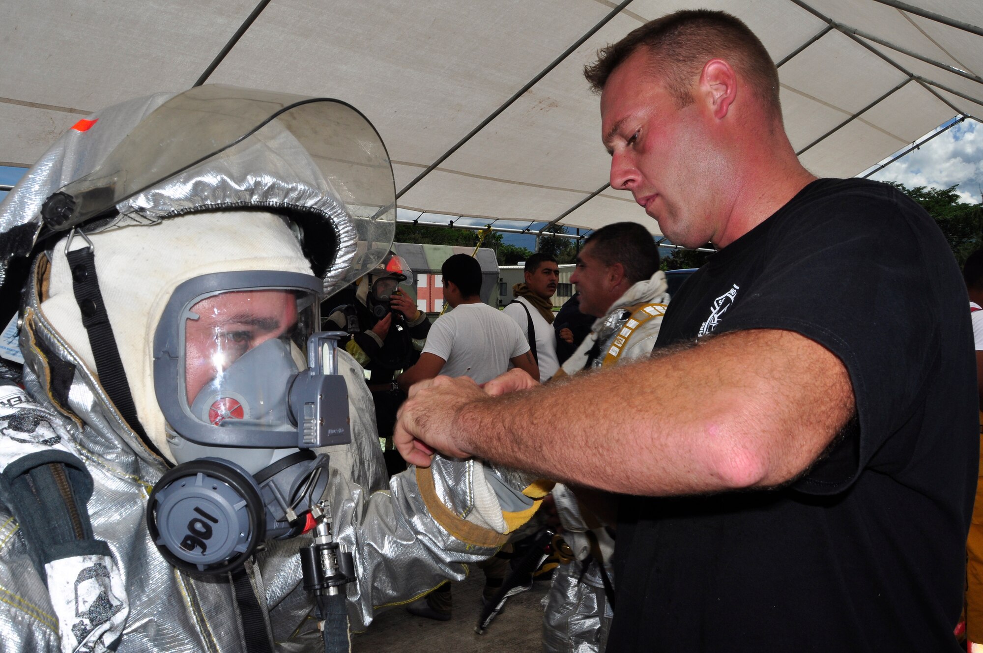 SOTO CANO AIR BASE, Honduras --  Staff Sgt. Justin Talbot, a 612th Air Base Squadron firefighter, fixes the personal protective equipment of a Honduran firefighter here during the Central America Sharing Mutual Operational Knowledge and Experiences exercise here Aug. 24. The course covered firefighter subjects including self-contained breathing apparatus training, first responder medical training, hot and cold medical evacuation patient loading, and aircraft and structural firefighting operations. (U.S. Air Force photo/Martin Chahin)
