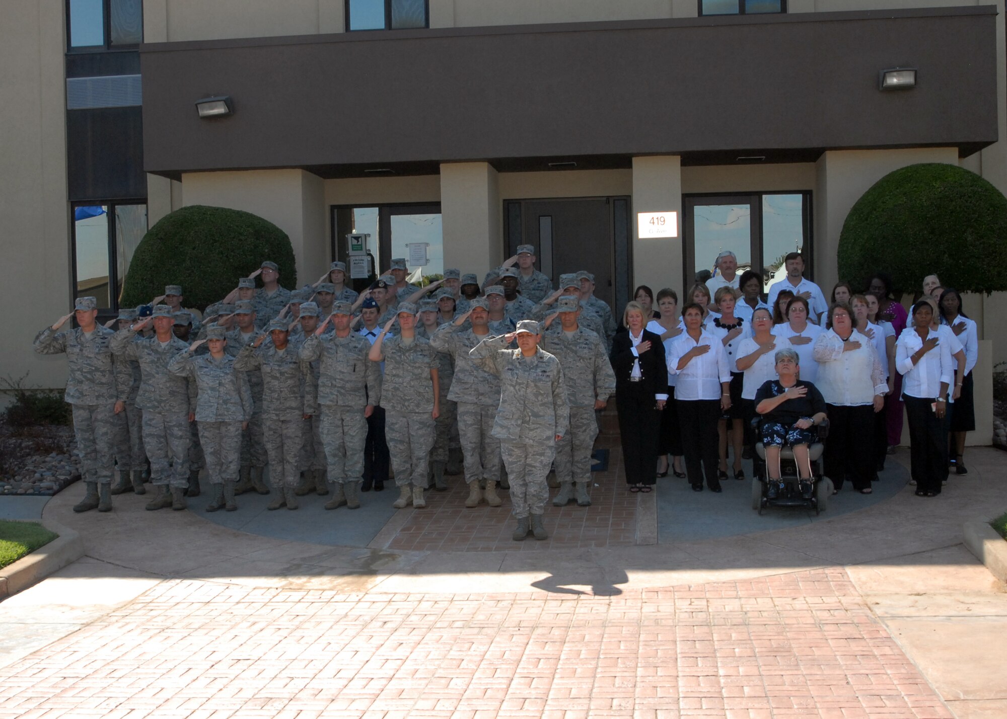 Civilian and military Sheppard members pay respects during retreat in front of the 82nd Training Wing Headquarters building, during the Women’s Equality Day formation Aug. 26. Team Sheppard held the event to commemorate the anniversary of the passage of the 19th Amendment in 1920, which granted women the right to vote. (U.S. Air Force photo/ Lou Anne Sledge)