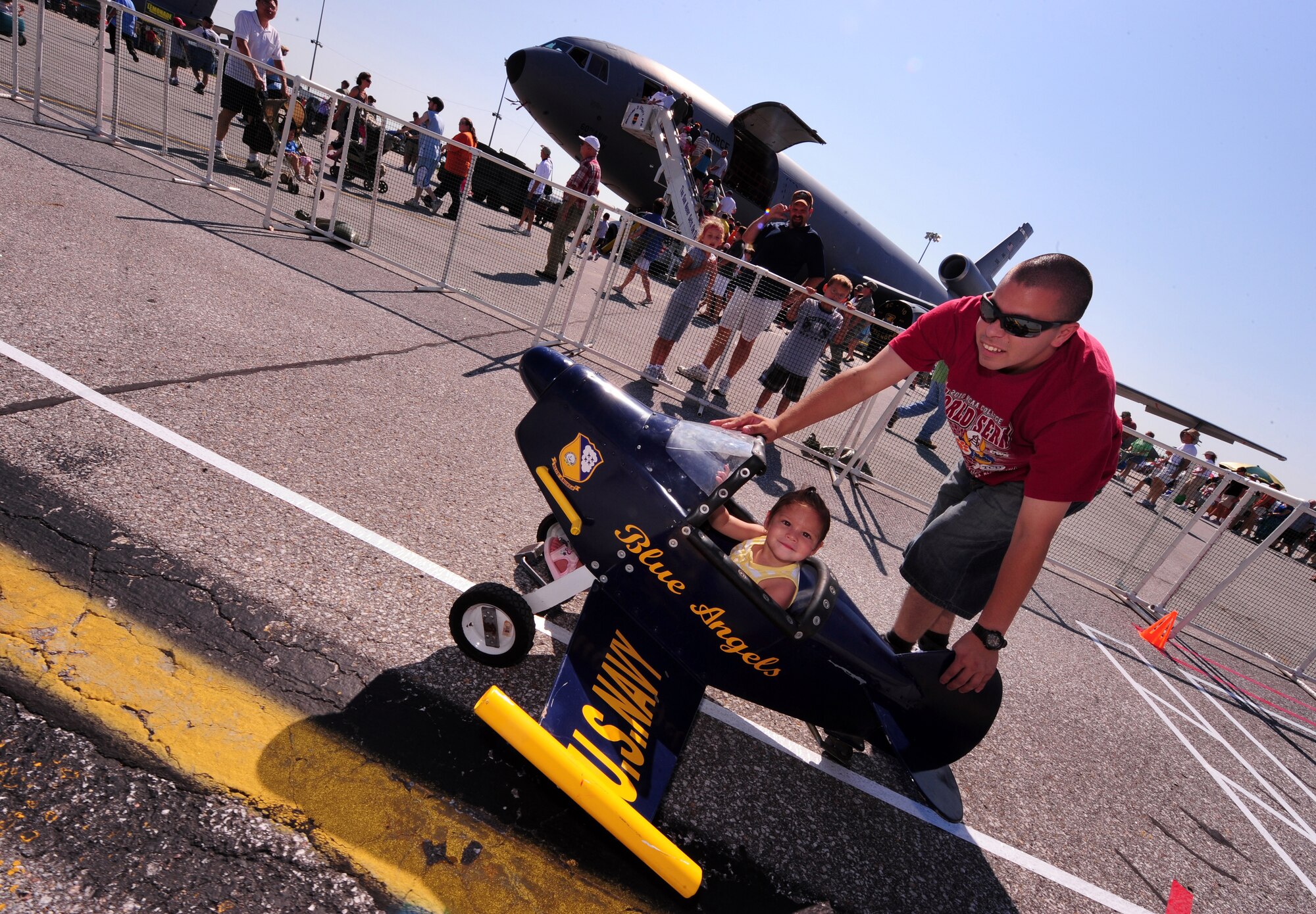 OFFUTT AIR FORCE BASE, Neb. - Airman 1st Class Adrian Guzman, 55th Communications Squadron, pushes his daughter Payton in a U.S. Navy Blue Angels peddle plane here, Aug. 28 as part of the 2010 Defenders of Freedom Open House and Air Show. The show provided numerous children's activities to include bounce castles, face painting and games. U.S. Air Force photo by Josh Plueger
