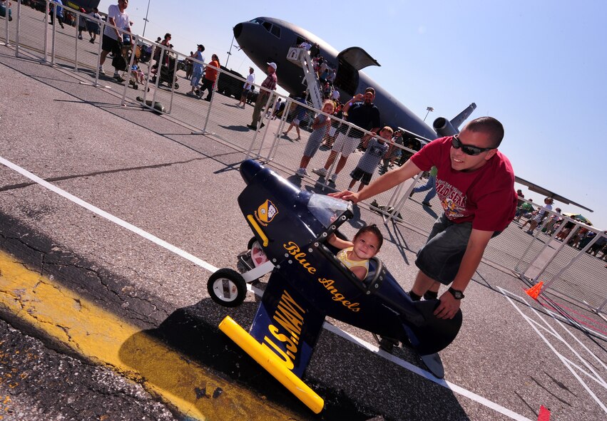 OFFUTT AIR FORCE BASE, Neb. - Airman 1st Class Adrian Guzman, 55th Communications Squadron, pushes his daughter Payton in a U.S. Navy Blue Angels peddle plane here, Aug. 28 as part of the 2010 Defenders of Freedom Open House and Air Show. The show provided numerous children's activities to include bounce castles, face painting and games. U.S. Air Force photo by Josh Plueger
