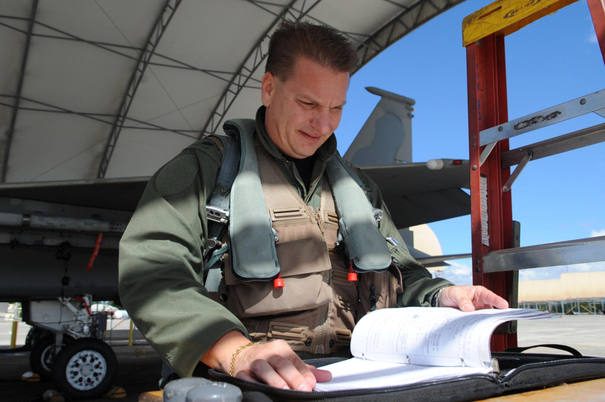 JOINT BASE PEARL HARBOR-HICKAM, Hawaii - F-15 Eagle pilot, Lt. Col Mark "Odie" Ladtkow of the 199th Fighter Squadron, Hawaii Air National Guard, Joint Base Pearl Harbor-Hickam, Hawaii reviews maintenance and flying hours on his jet before conducting his last F-15 training mission on Aug. 25 at Hickam. The 199th is transitioning from the F-15 to the F-22 Raptor, which is a fifth generation fighter. The 199th has flown the F-15 since 1987 and received their first two Raptors on July 9, 2010.  (U.S.  Air Force photo/Tech Sgt. Cohen A. Young)