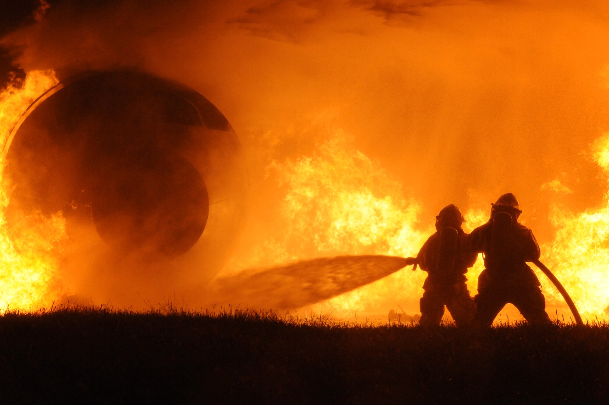 WHITEMAN AIR FORCE BASE, Mo. -Senior Airman Rocky Vasquez and Airman 1st Class David Pacheco, 509th Civil Engineer Squadron firefighters, man a hand line to extinguish a simulated aircraft fire at the Whiteman fire pit, Aug.23. The hand line is brought in after a fire has been depleted by the trucks to help extinguish the rest of the flames.(U.S. Air Force photo by Senior Airman Carlin Leslie) 