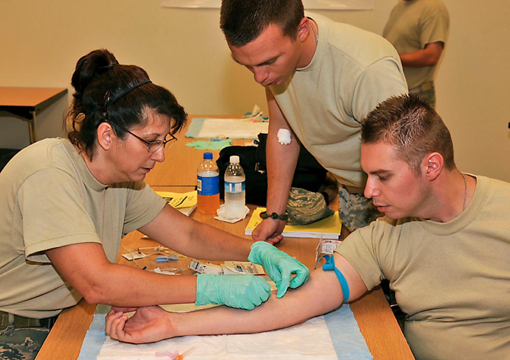 Tech. Sgt. Samm (right) draws blood from Staff Sgt. Love (left) while the instructor watches during Combat Lifesavers Course. Photo by Master Sgt. John Day