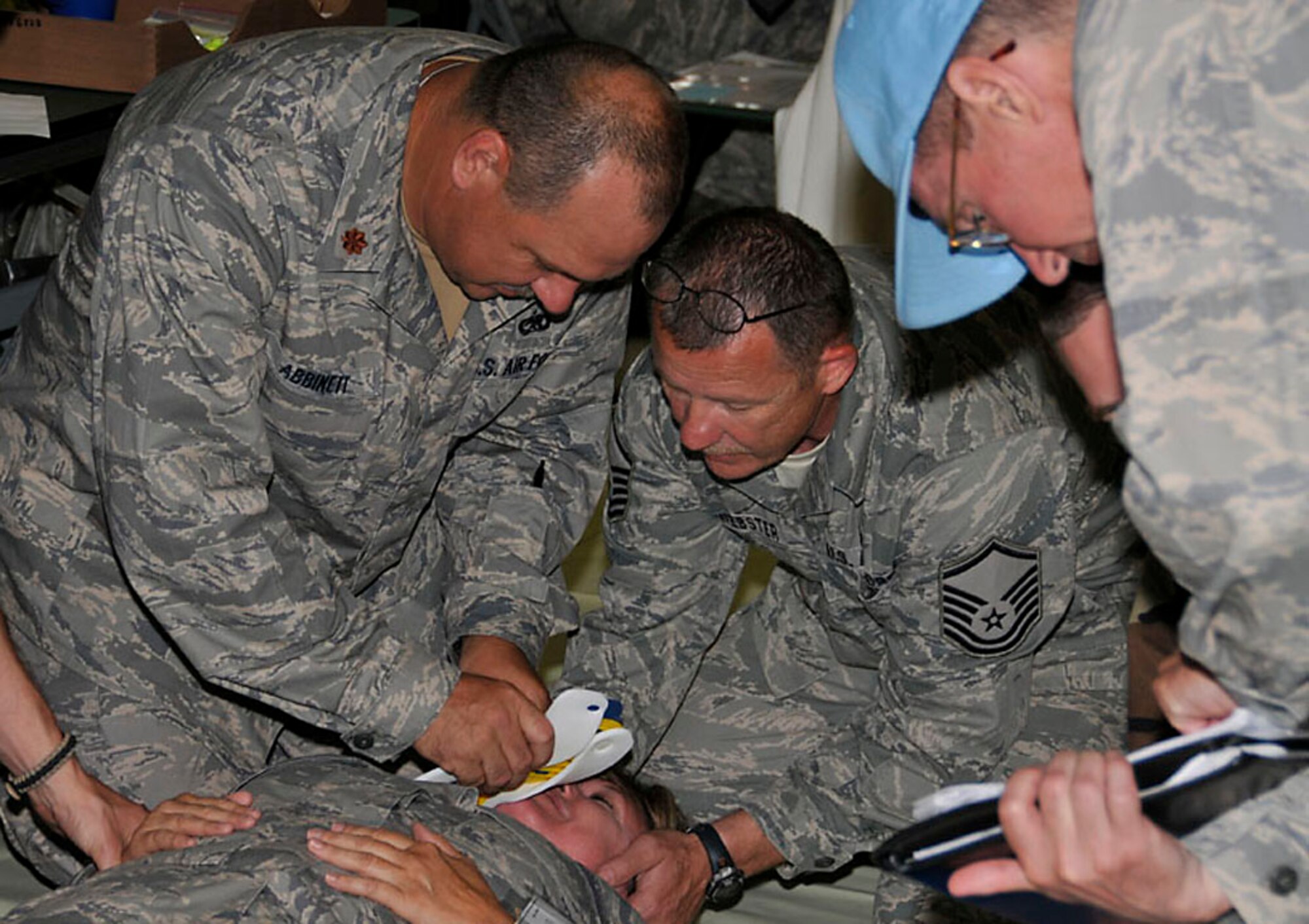 Maj. Abbinett (left) and Master Sgt. Webster (center), place a C collar around the neck of a patient during the exercise. Photo by Master Sgt. John Day