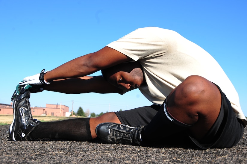 ELLSWORTH AIR FORCE BASE, S.D. -- Airman Reginald Cummings, 28th Aircraft Maintenance Squadron integrated flight control systems apprentice, stretches before a football practice, Aug. 26.  Stretching before and after sports related exercises can reduce the possibility of injury. (U.S. Air Force photo/Airman 1st Class Anthony Sanchelli)