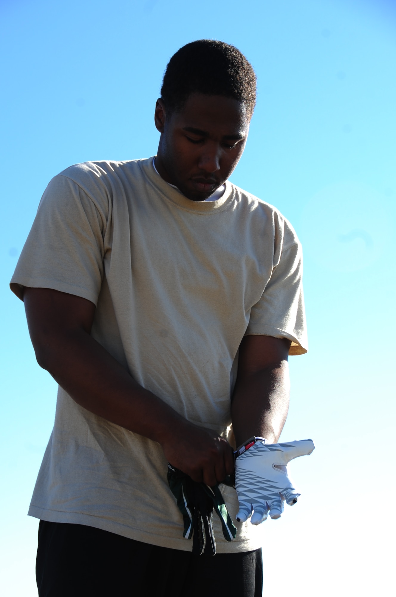 ELLSWORTH AIR FORCE BASE, S.D. -- Airman Reginald Cummings, 28th Aircraft Maintenance Squadron integrated flight control systems apprentice, fastens his gloves on before a football practice, Aug. 26.  Wearing the proper equipment while undergoing sports is essential to avoiding injury. (U.S. Air Force photo/Airman 1st Class Anthony Sanchelli)