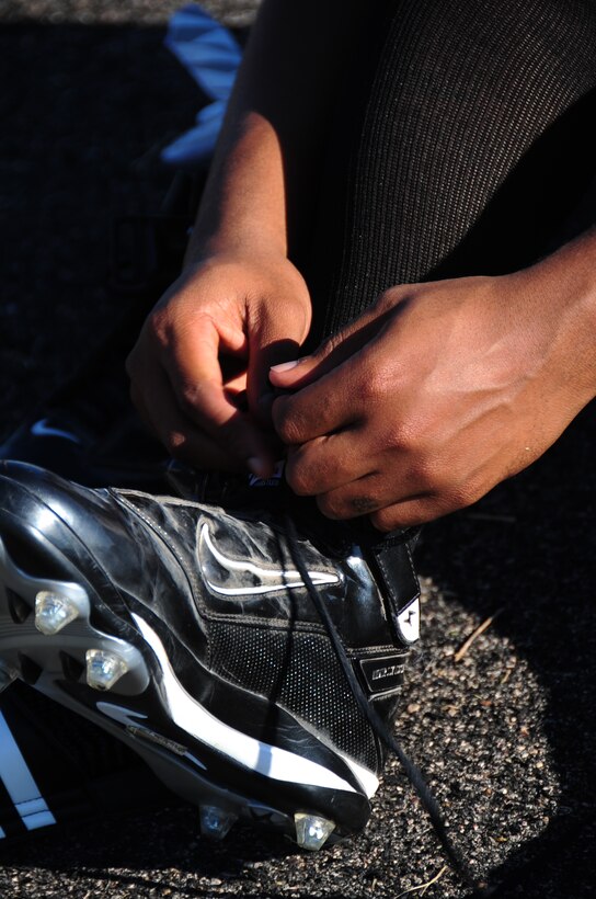 ELLSWORTH AIR FORCE BASE, S.D. -- Airman Reginald Cummings, 28th Aircraft Maintenance Squadron integrated flight control systems apprentice, ties the laces on his cleats before football practice, Aug. 26.  It's important to wear the proper equipment when playing sports to avoid sustaining injuries. (U.S. Air Force photo/Airman 1st Class Anthony Sanchelli)